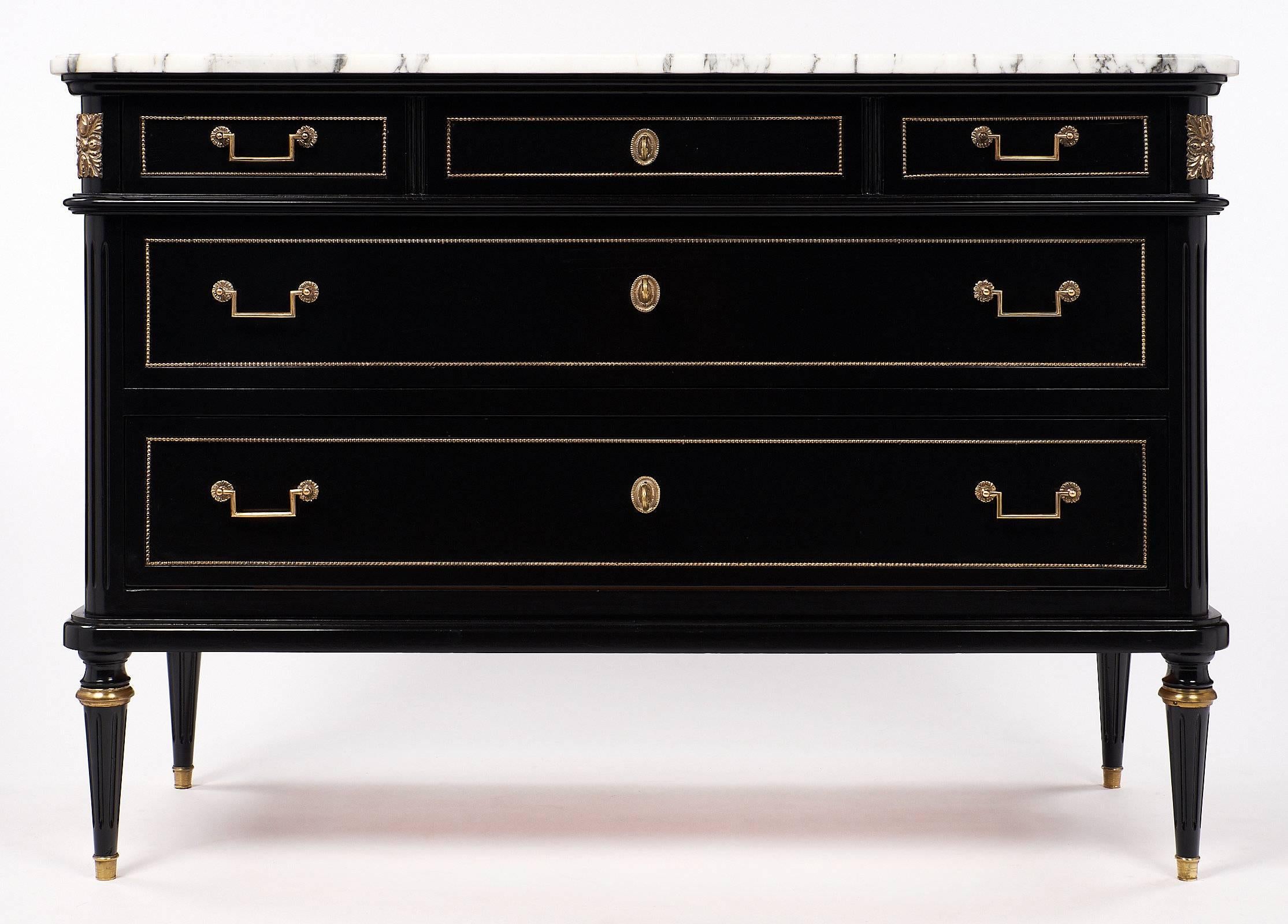 Lovely Louis XVI style chest with wonderful brass trim details and an intact Carrara marble slab top. The mahogany piece has been ebonized and finished with a lustrous French polish. There are two large drawers topped by three smaller drawers. The