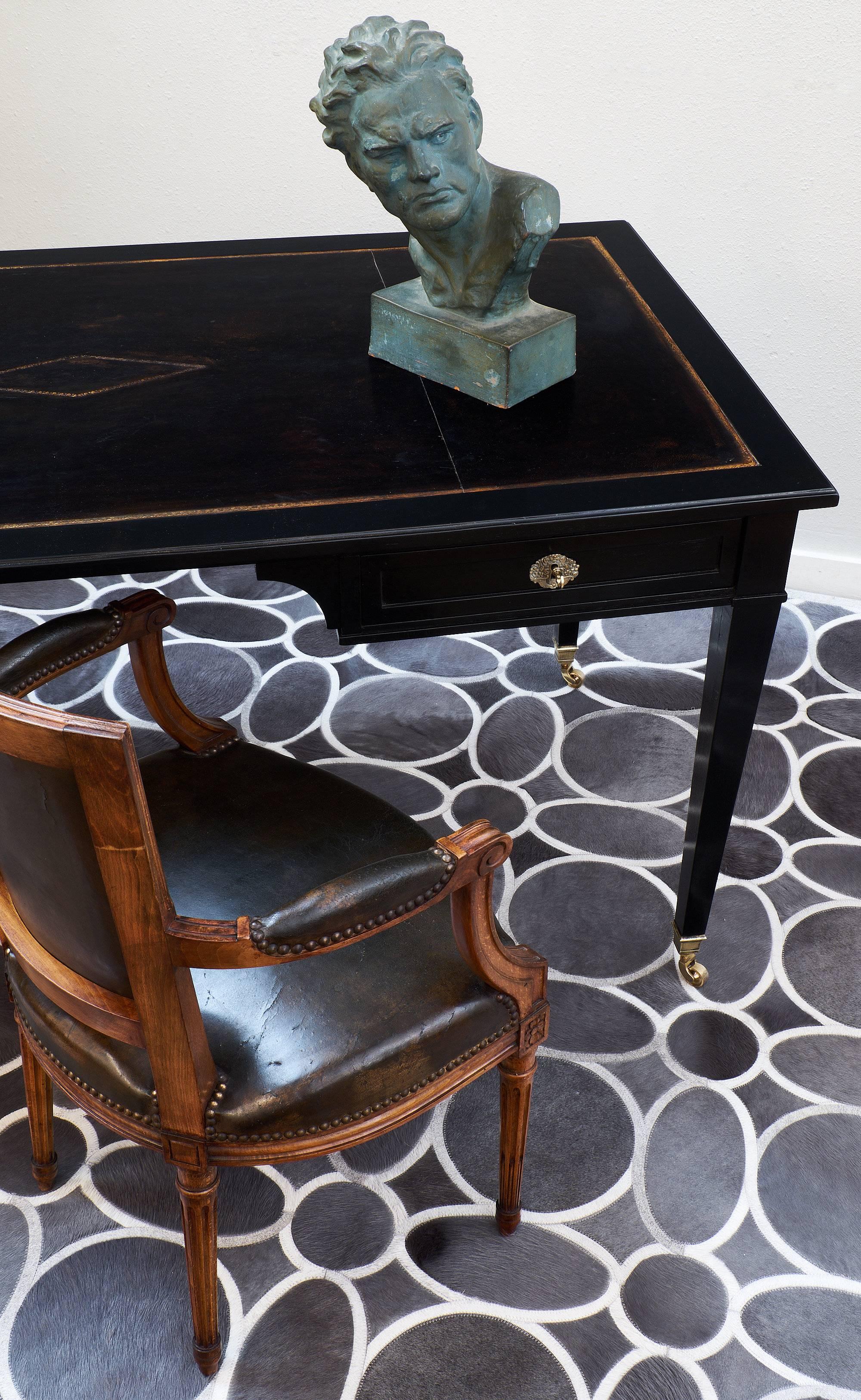 Elegant Directoire style desk from France made of ebonized mahogany that has been finished with a museum quality French polish for high luster. This desk has perfect proportions and features an espresso colored leather writing surface across the