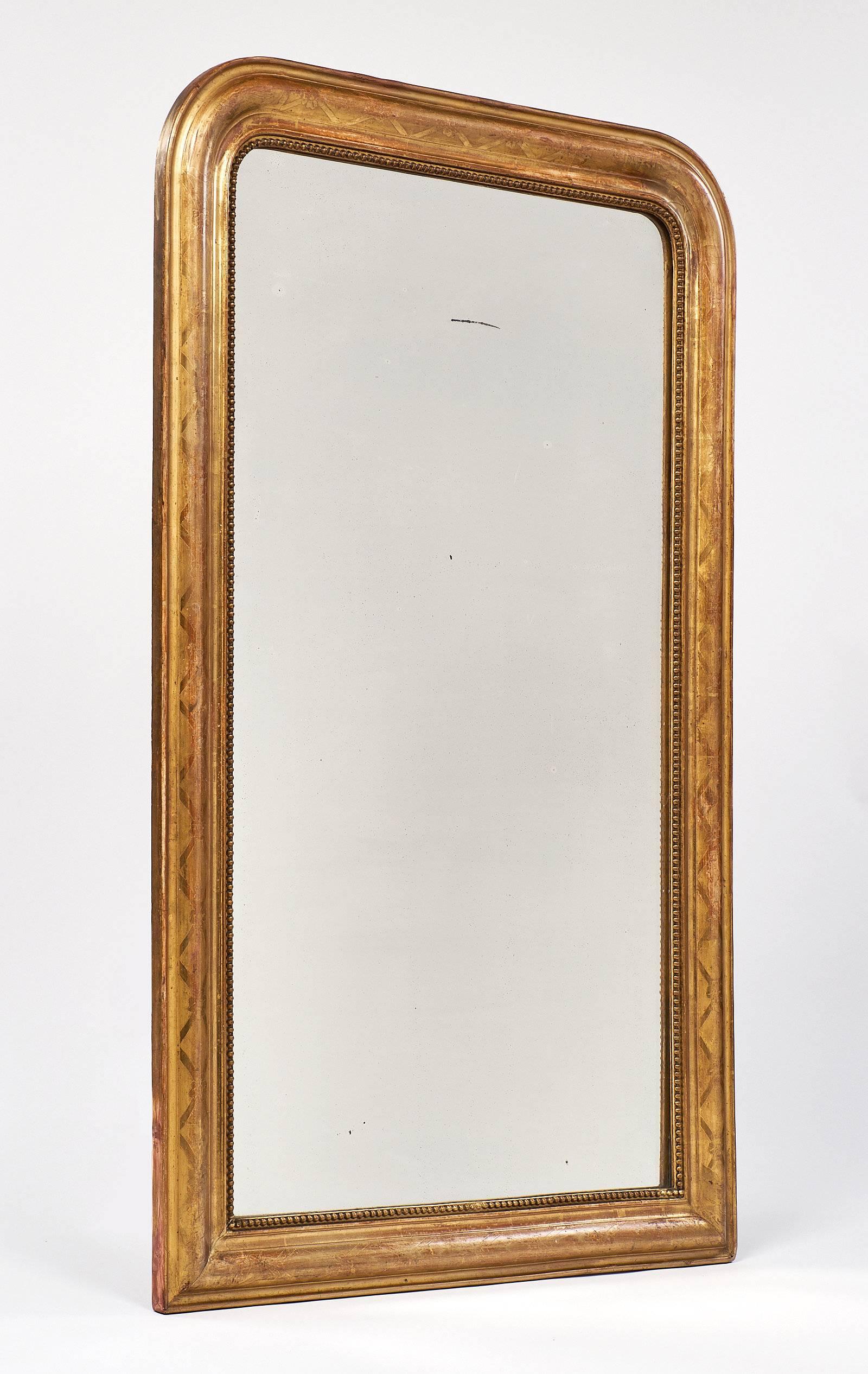 Wonderful Louis Philippe mirror with the iconic rounded upper corners. This piece has the original mercury glass mirror in fantastic condition. The frame is gold leafed with a beautiful floral motif. The frame also has beading surrounding the mirror