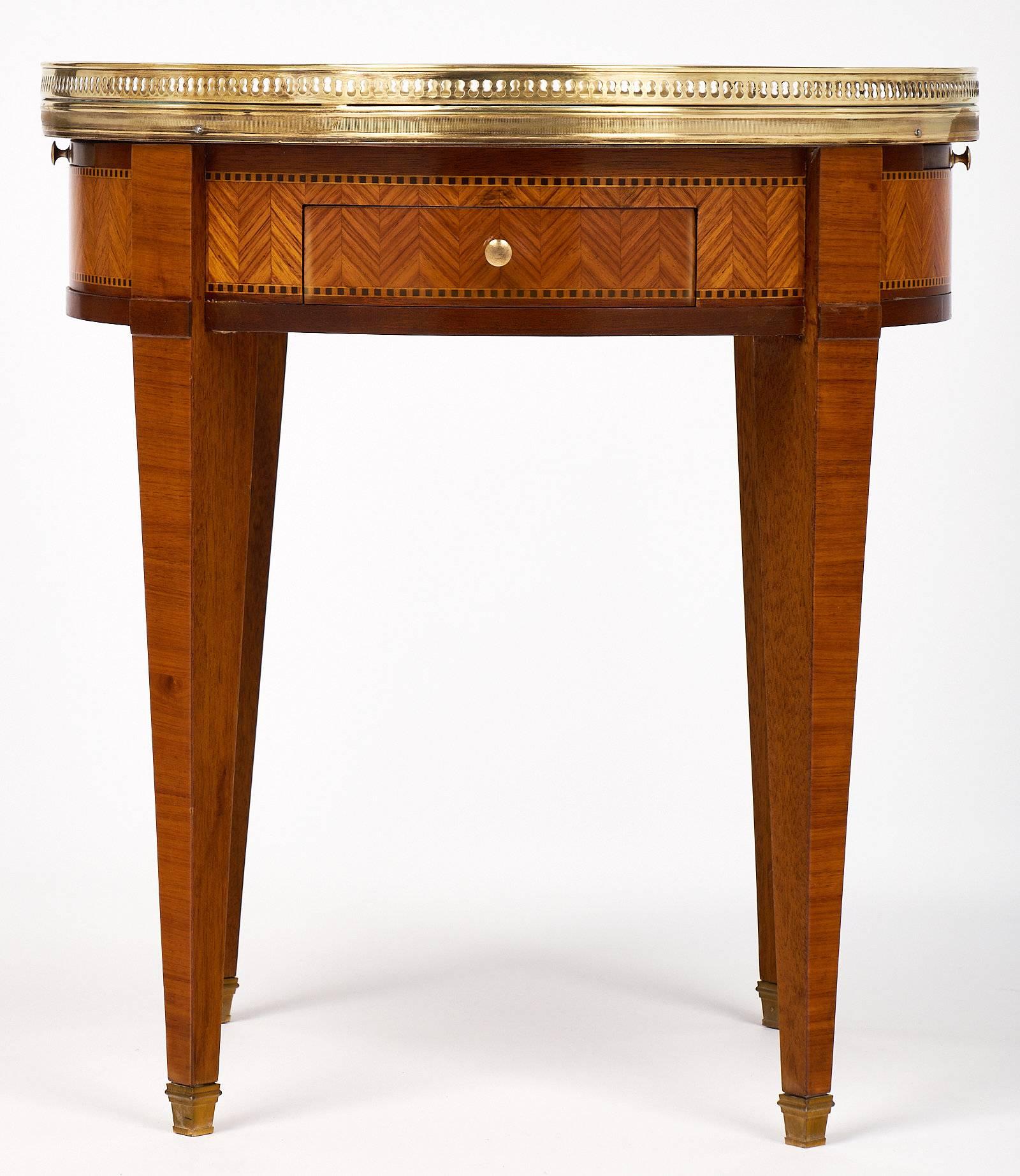 Elegant Louis XVI style bouillotte table with a fantastic Carrara marble-top and pull-out leaves. The table is made of rosewood and mahogany and features a beautiful chevron parquetry. There is a brass gallery that draws the eye to the table, and