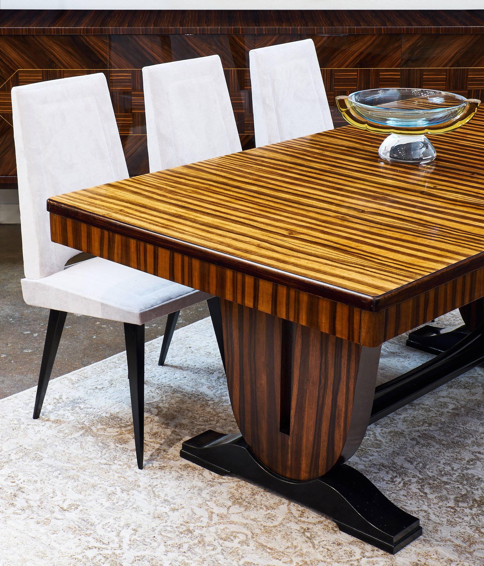 An incredible piece from the French Art Deco period, this dining table is a strong and dynamic additional to a home. The Macassar of Ebony wood is very striking with prominent and beautiful grain throughout. It features a great double pedestal base
