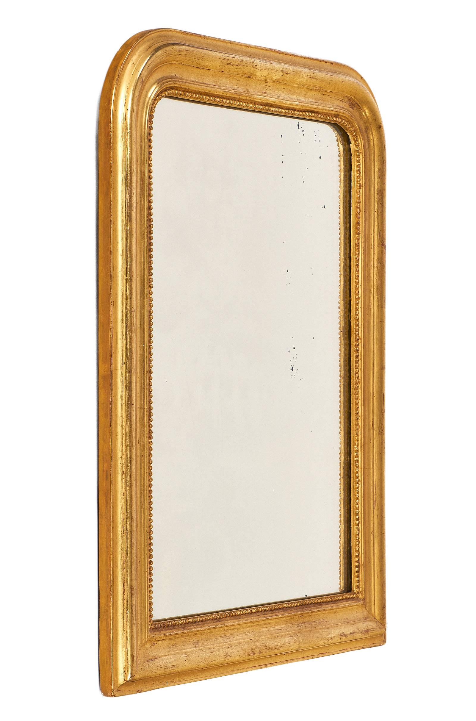 Elegant Louis Philippe mirror in excellent condition and small in size. This piece has the lovely curved upper corners of the Louis Philippe style and the original antique mirror. The frame has beading around the interior, and the small stature