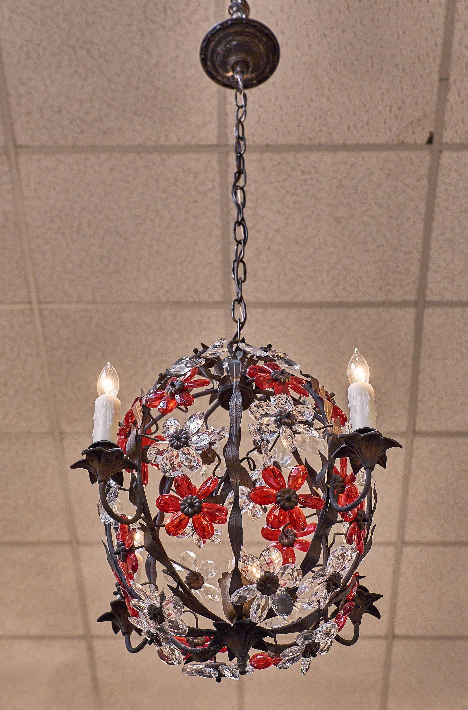 A unique and highly decorative pair of chandeliers, boasting four arms around a cage-like structure and a combination of clear and ruby red finely cut crystal flowers. These fixtures require four candelabra-base bulbs and have been wired to fit US