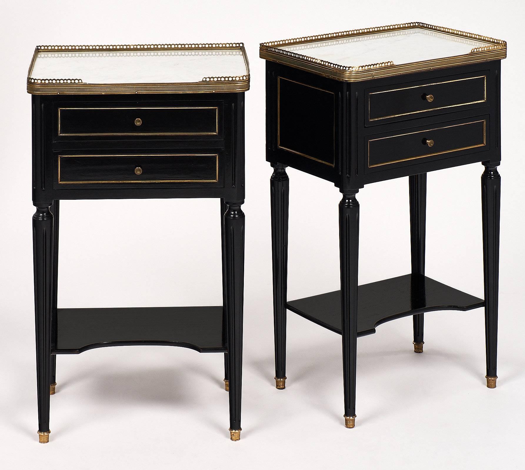 French Louis XVI style pair of mahogany side chests with beautiful Carrara marble tops, gilded brass galleries, and gilt brass trims throughout. The legs are tapered with brass feet. These will be perfect companions for your living area or guest bed