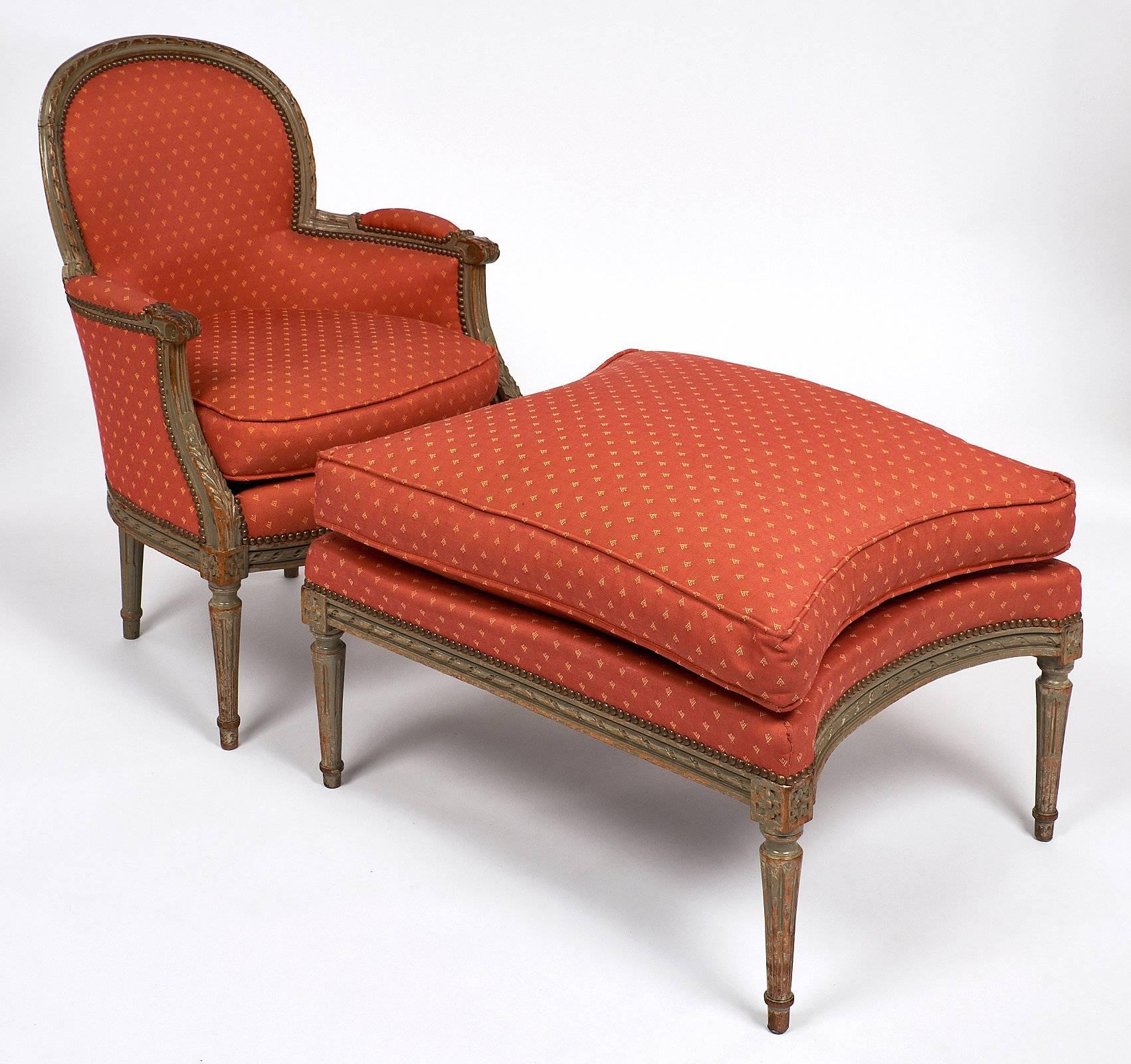 Elegant bergère with a large ottoman for a relaxing seat. This beautiful piece has the original salmon colored upholstery throughout. The frame has detailed hand-carved leaf work and fluted, tapered legs. The curved arms and rounded back add