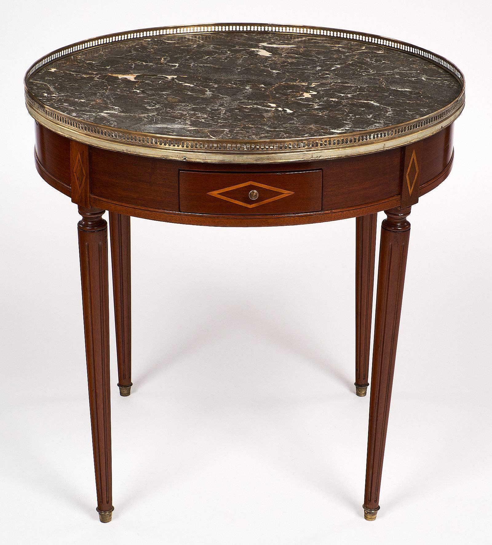 Antique Louis XVI style bouillotte table with a beautiful Sainte Anne marble top, pull out leaves and drawers. This elegant table made of mahogany, features diamond shaped inlays. There is a brass gallery that draws the eye to the table, and all