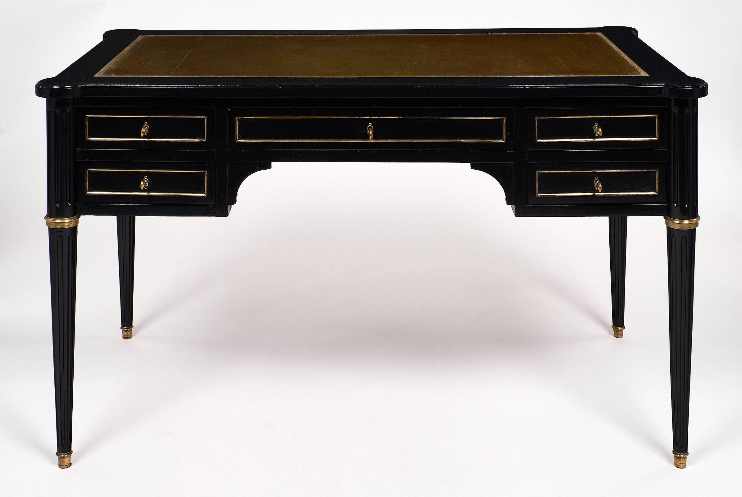 Handsome Louis XVI style desk with a superb leather writing surface. This mahogany piece has been ebonized and finished with a French polish finish for luster. The leather surface has an embossed, gold leafed frieze border. The desk has a pullout