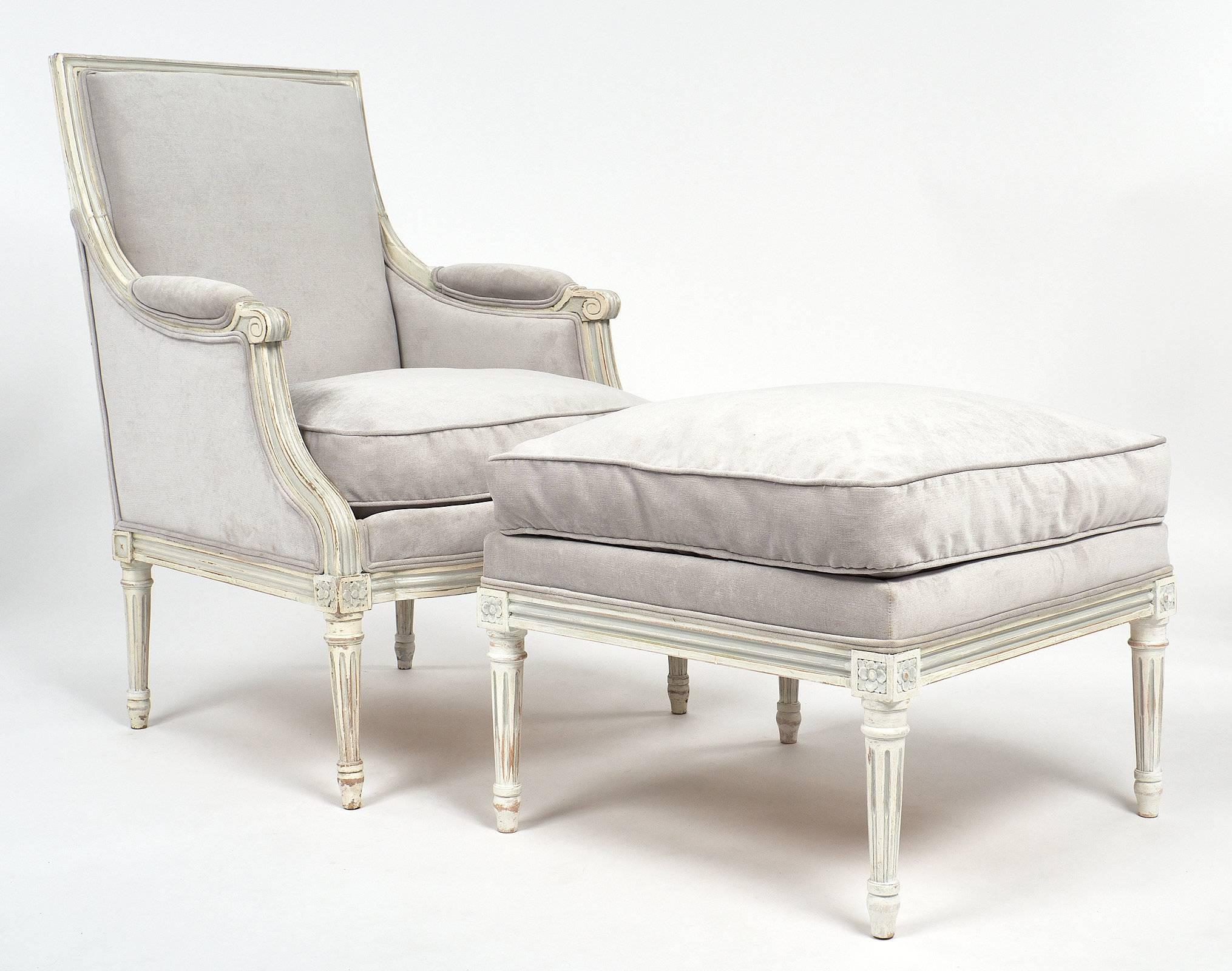 Antique bergère with matching ottoman for an elegant and comfortable set up to sit and relax. The legs show hand-carved fluting in the tapering and frame. White and grey milk paint finish beautifully patinated add depth and character to this set.