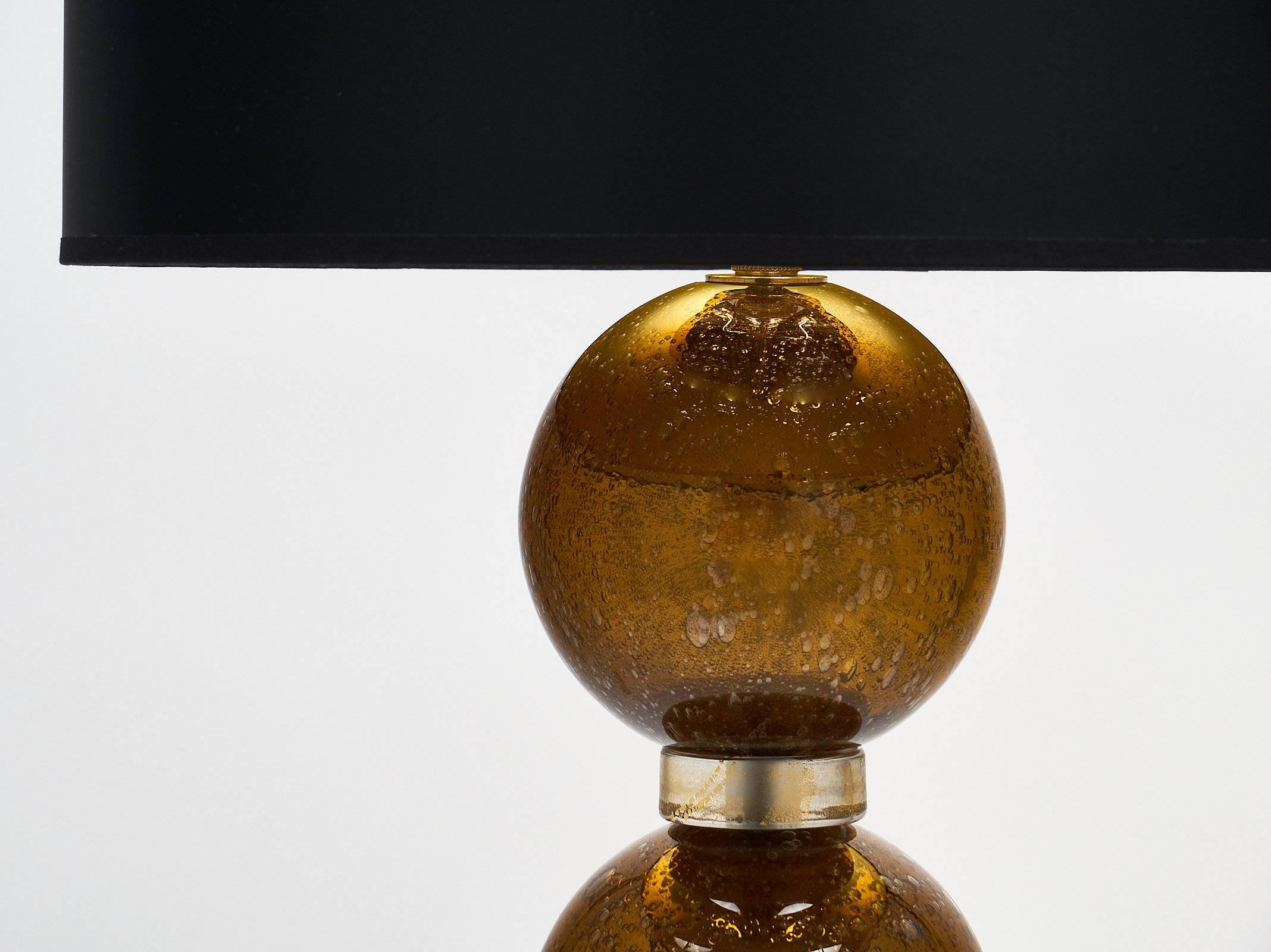 Handblown Murano glass lamps with spheres of amber glass backed with gold leaf. Each sphere has also been created using the “Pulegoso” effect, leaving bubbles in the glass for texture and depth. The glass pieces between each sphere have 23-karat