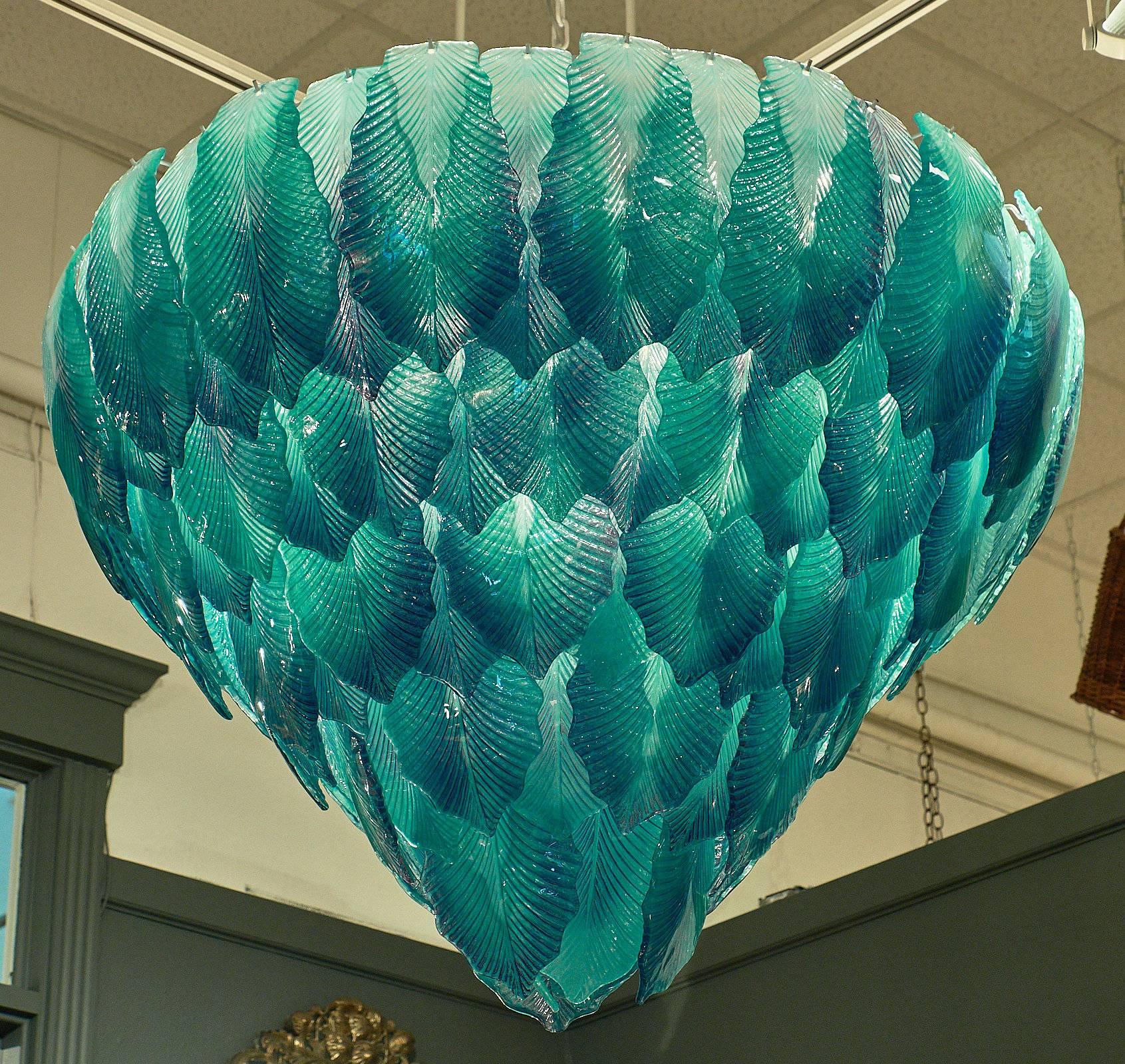 Stunning Murano glass chandelier with layered leaves of handblown glass. This piece is a striking blue in color with intricate details on each glass leaf. The impressive fixture has five layers of overlapping pieces in a tiered shape. This