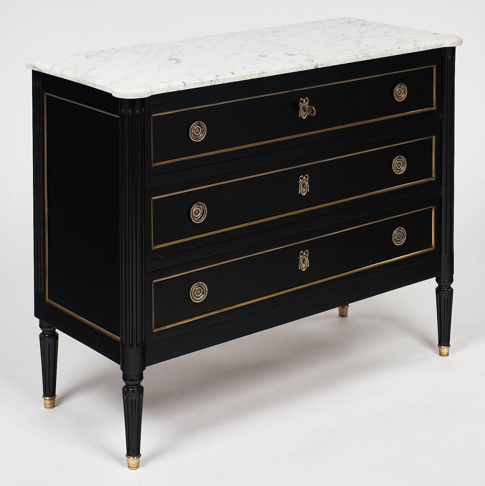 French antique Louis XVI style chest with original Carrara marble top. This 19th century mahogany piece is ebonized and finished with a hand-rubbed French polish. The brass hardware is all original, and the single key works to lock all three drawers.