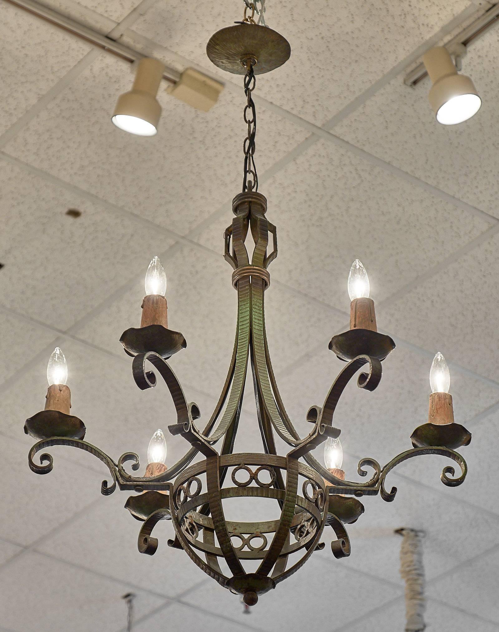 Art Deco period forged iron chandelier with six arms. This traditional piece has a green tone to the metal, and a strong appeal with curved elements holding the bobeches . This fixture has been wired to fit US standards.