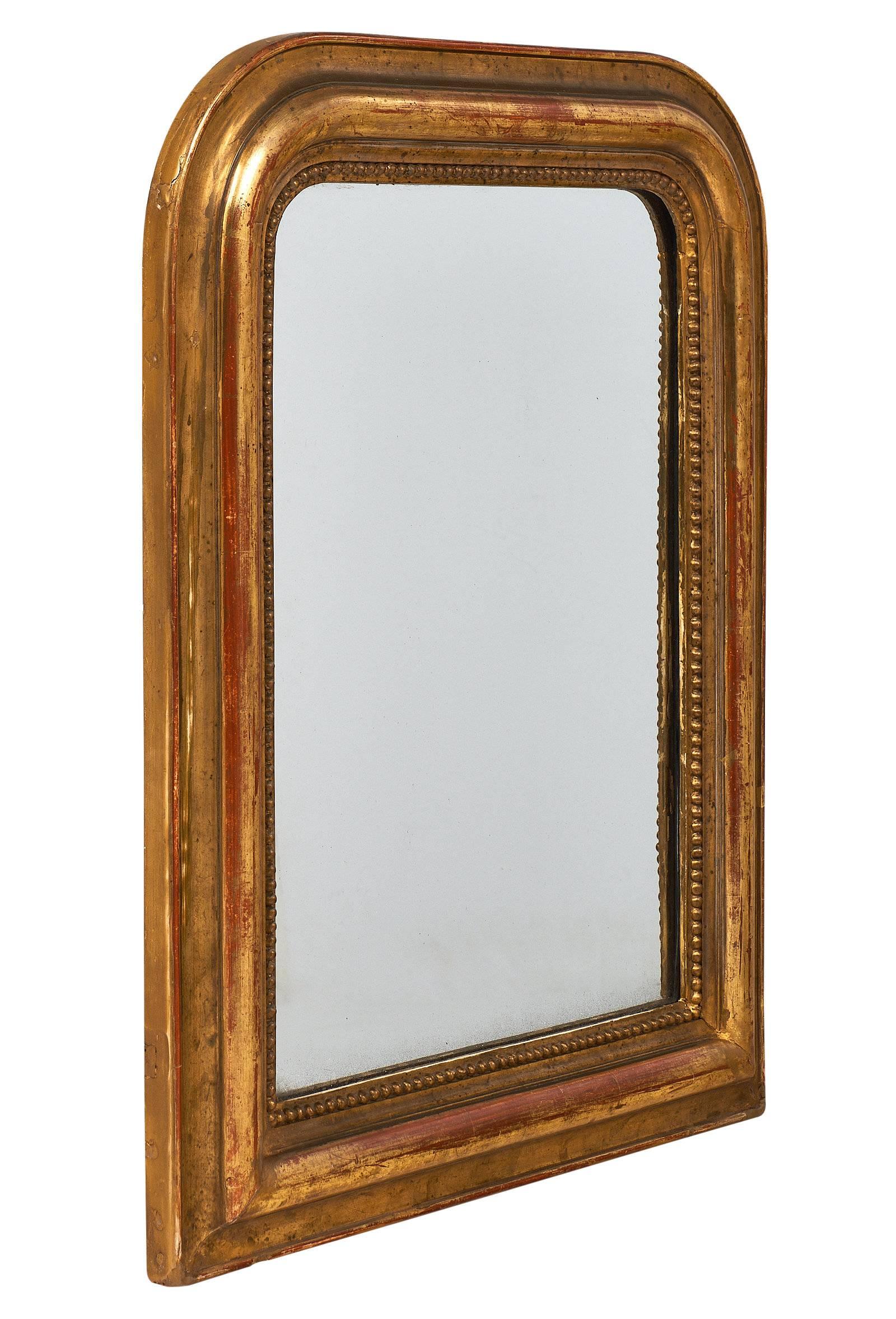 Lovely mirror from the Louis Philippe period with the original mirror. This small piece has a hand-carved frame with beading surrounding the original mirror, and a striking patina. The frame also has the characteristic curved upper corners of the