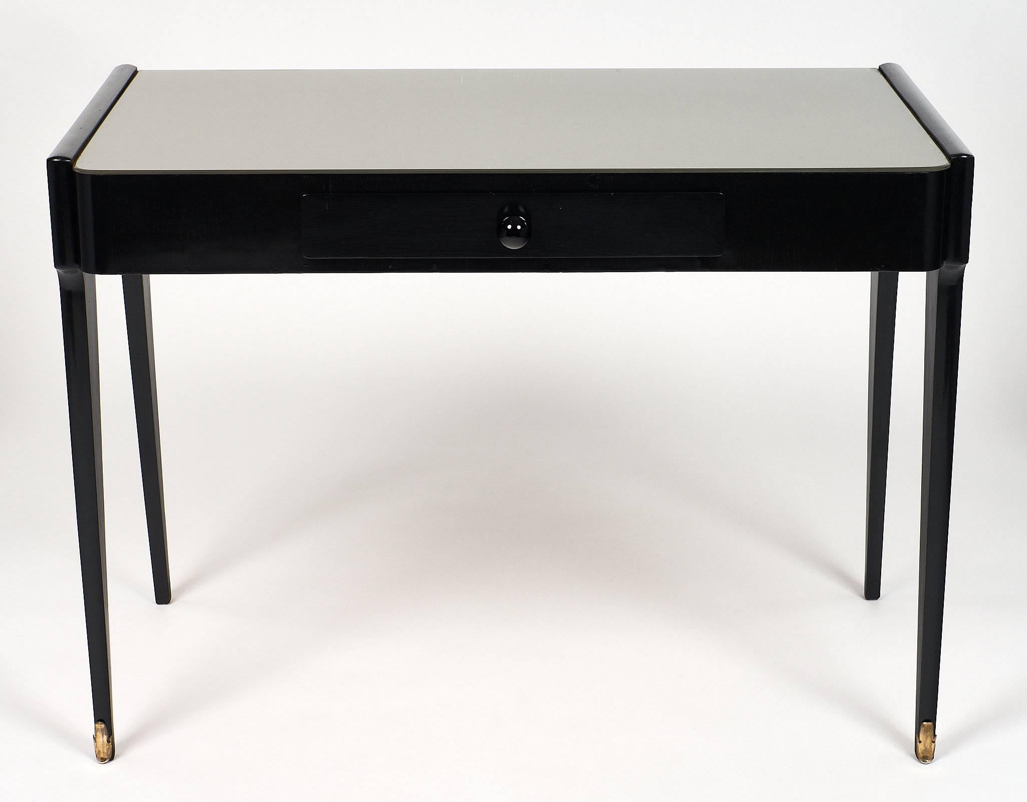 Italian mid-century desk made of ebonized mahogany that has been finished with a French polish for a lustrous appearance. The top is covered with glass that has a frosted, metallic coloring. The front of the desk has one drawer with a Murano black