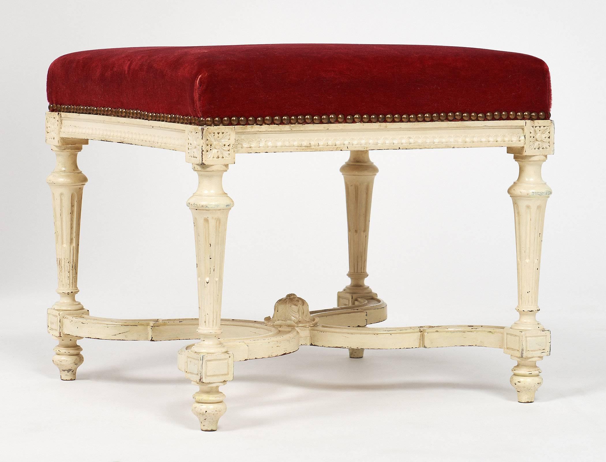 Fine French antique Louis XVI style bench with hand-carved, refined details. It features four tapered legs, an X-stretcher and the original red velvet upholstery. The paint is original and in good condition.