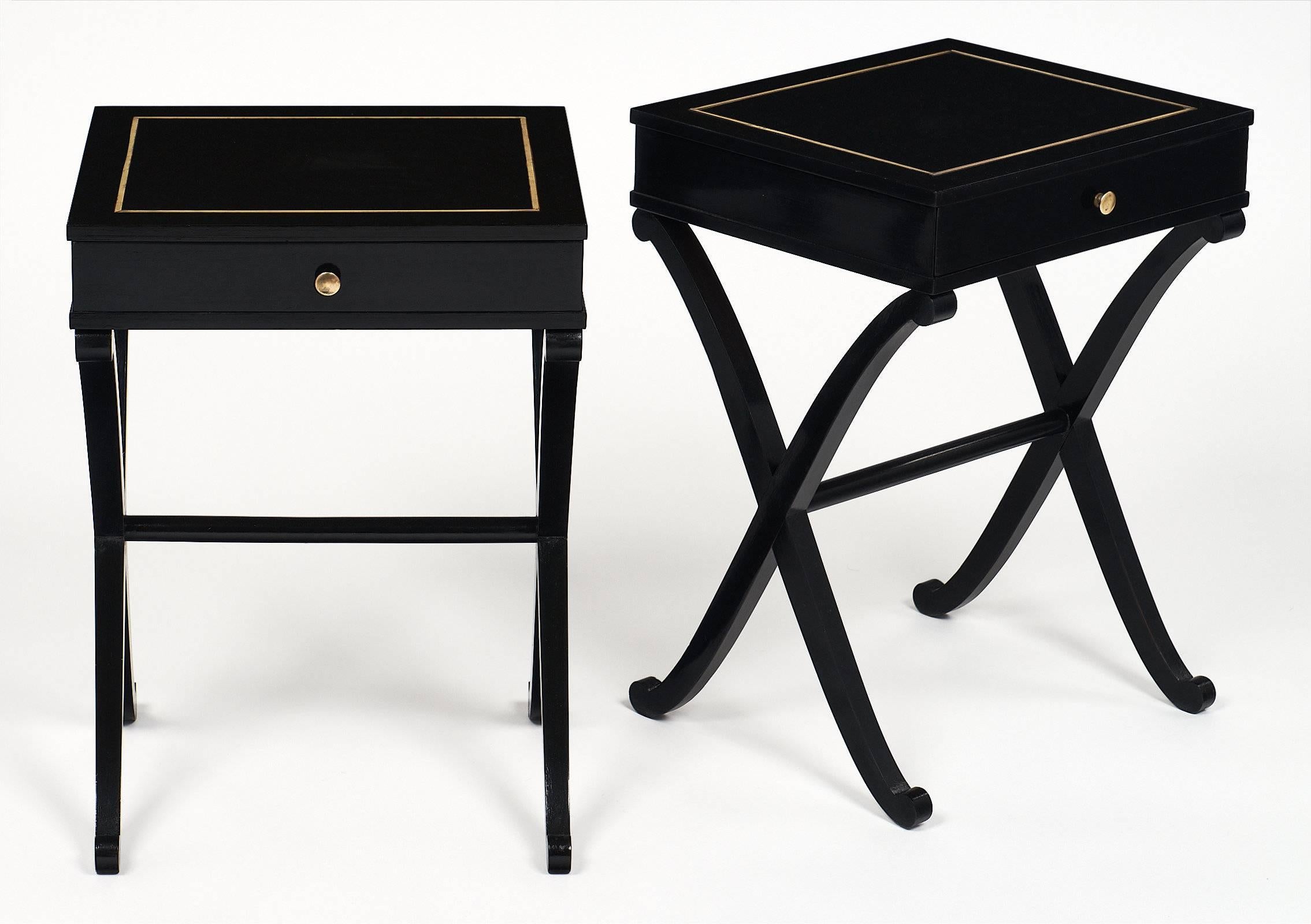 A French gracefully proportioned pair of side tables of ebonized mahogany and French polished to a high lustre finish. The tops feature gilt brass inlays. We loved the X-shaped legs, and the quality of the craftsmanship which shows in every details.