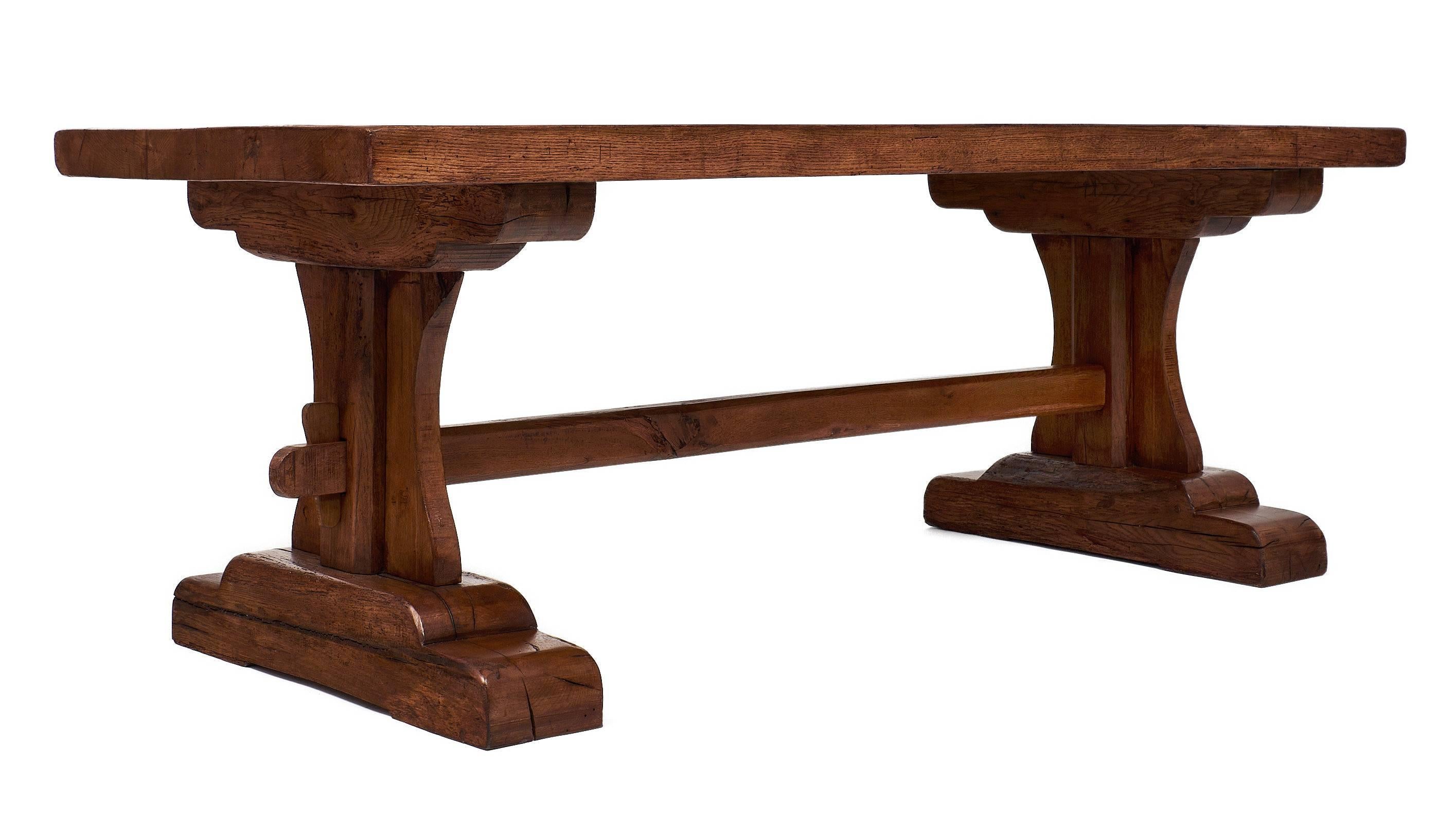 Strong, beautiful French monastery table of solid oak from Beaune in burgundy with a hand rubbed wax finish. We loved the thick wood slab on top of the bold pedestals, the stretcher holds them together with keys on both ends. Although very stabile,