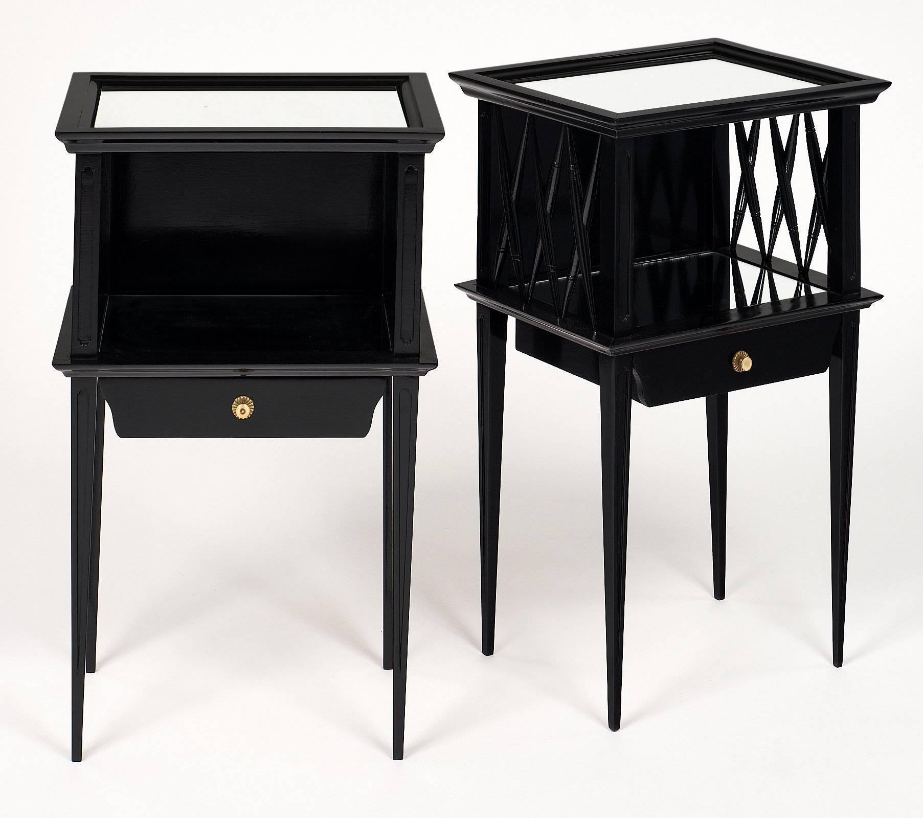 A pair of fine ebonized and French polished side tables in the Directoire style featuring a dovetailed drawer with a gilt brass pull, two mirrored shelves, and a niche sided with X lattice work. We loved the elegant refined look of these two