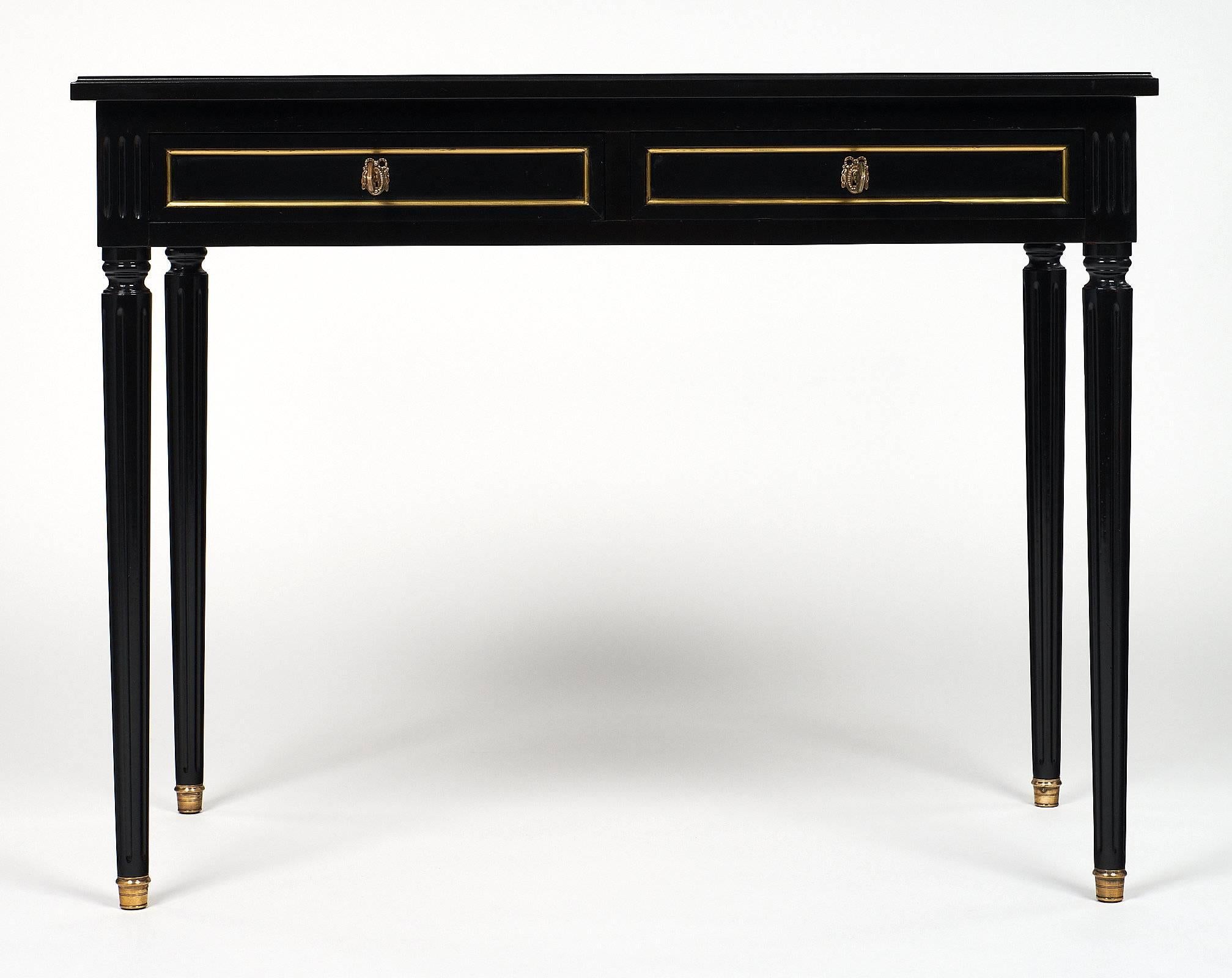 Charming French Louis XVI writing desk made of mahogany, sitting on four tapered and fluted legs. The wood has been ebonized and finished with a lustrous French polish. The top and extensions are covered with a rich Moroccan leather original to the