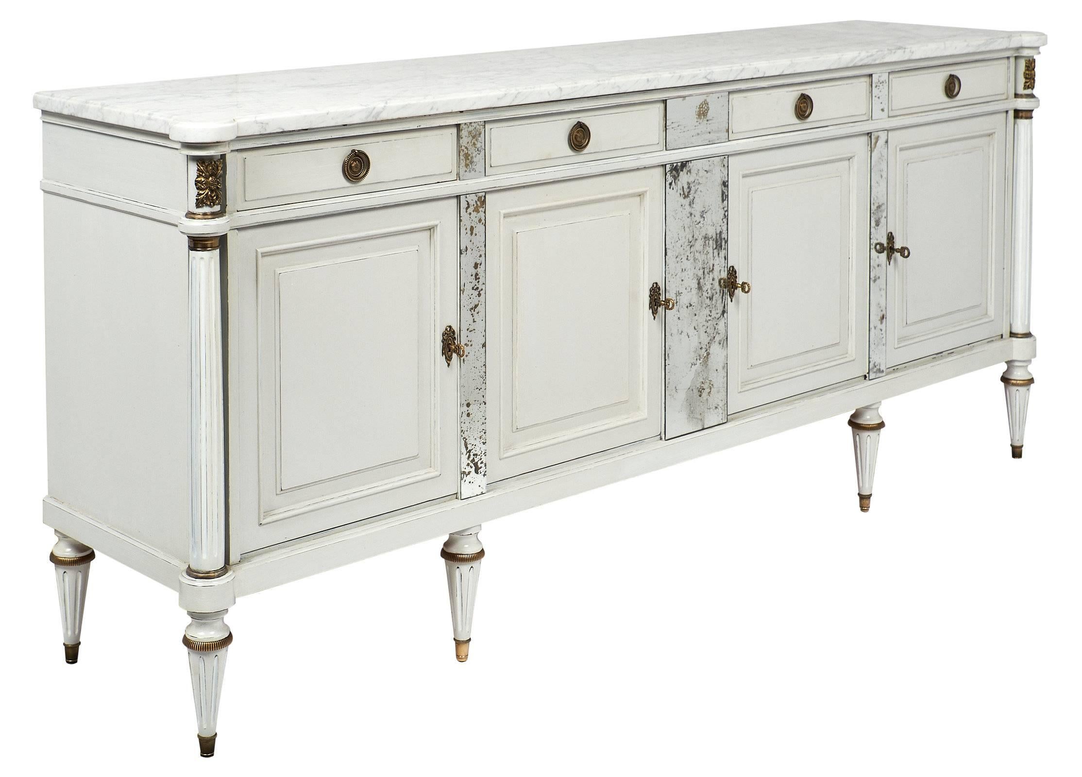A Louis XVI cherrywood buffet or credenza painted in dove gray and white with four doors and four drawers. There are adjustable shelves inside, and the piece is topped with an impressive veined white Carrara marble slab. It also features side fluted