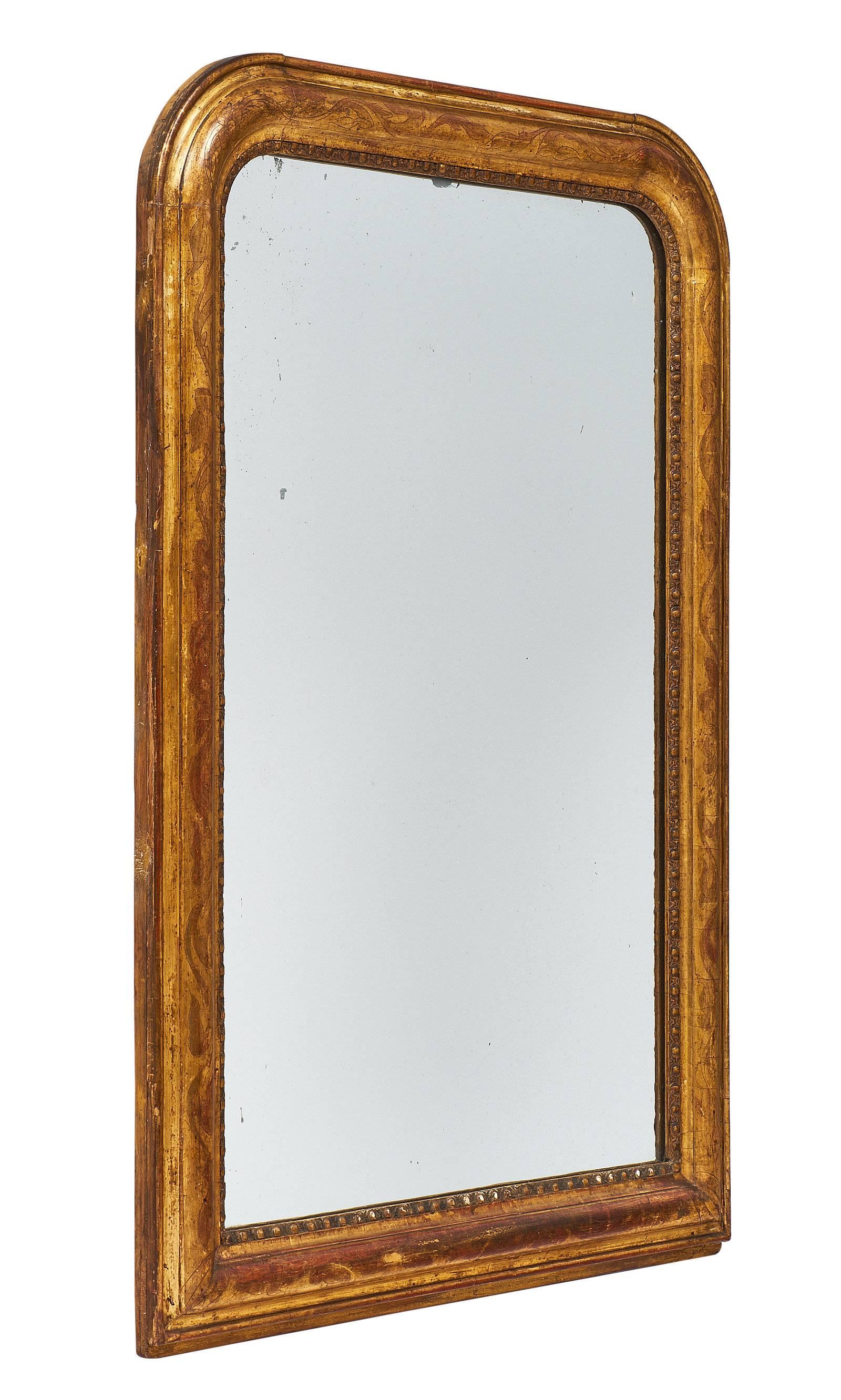 An original mid-19th century mirror from the Louis Philippe era. The mirror is original and the frame is in beautiful condition, showing a perfect patina. The sienna colored glaze coming through the 23-karat gold leafing creates a luminous and warm