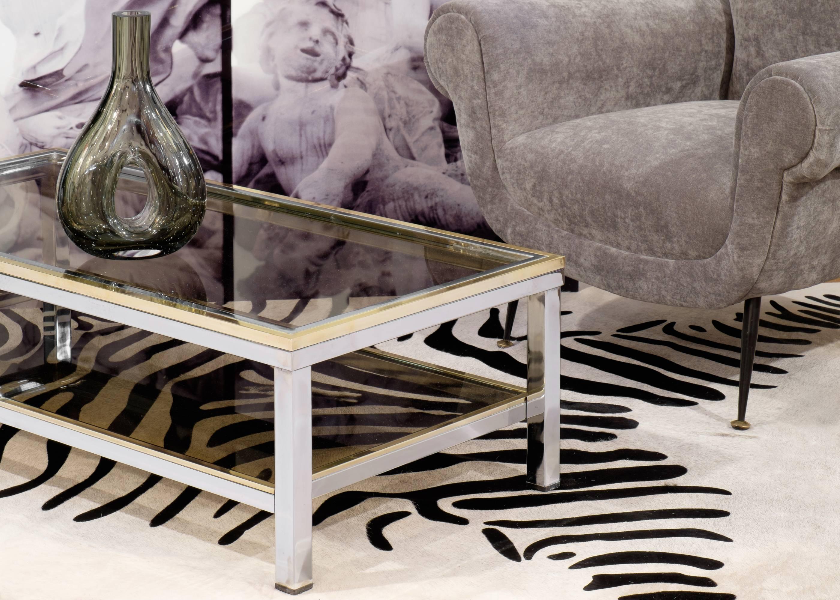 A sleek Romeo Rega attributed coffee table in chrome metal with brass accents surrounding the top. Smoked glass adds to the seductive elegance of this Mid-Century piece.