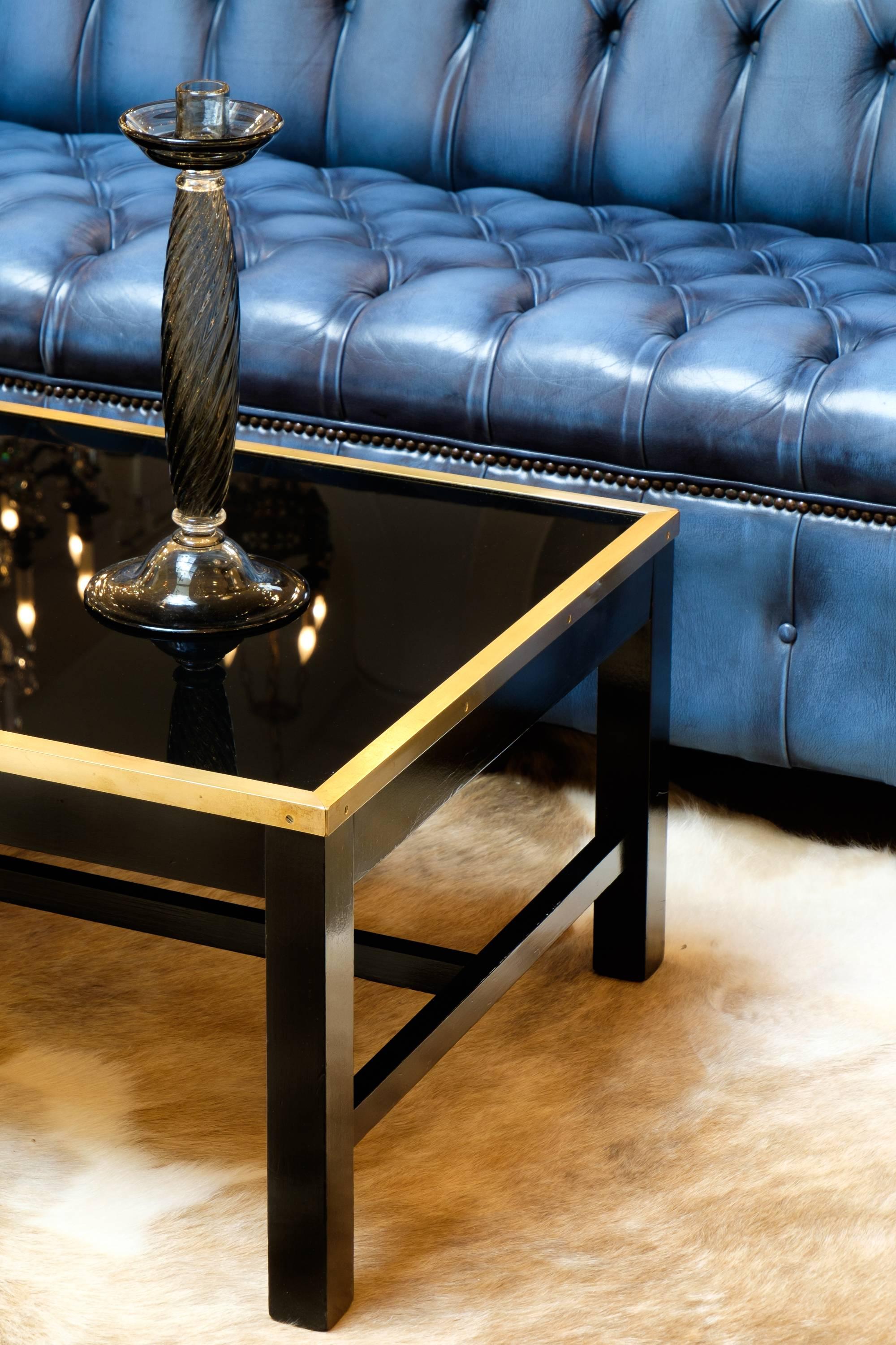 French vintage coffee table with a black glass top encased in brass, ebonized wood frame with a lustrous French polish finish. Clean lines and the finest craftsmanship really make this piece a keeper.