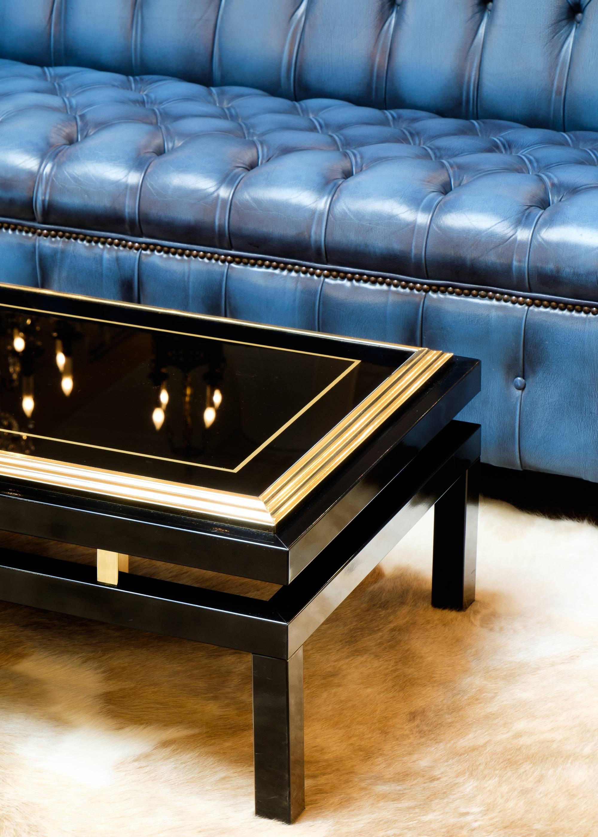Vintage French coffee table in black metal with brass accents and a black opaline glass top with gold accent. We love the floating quality of the top, supported by polished brass blocks.