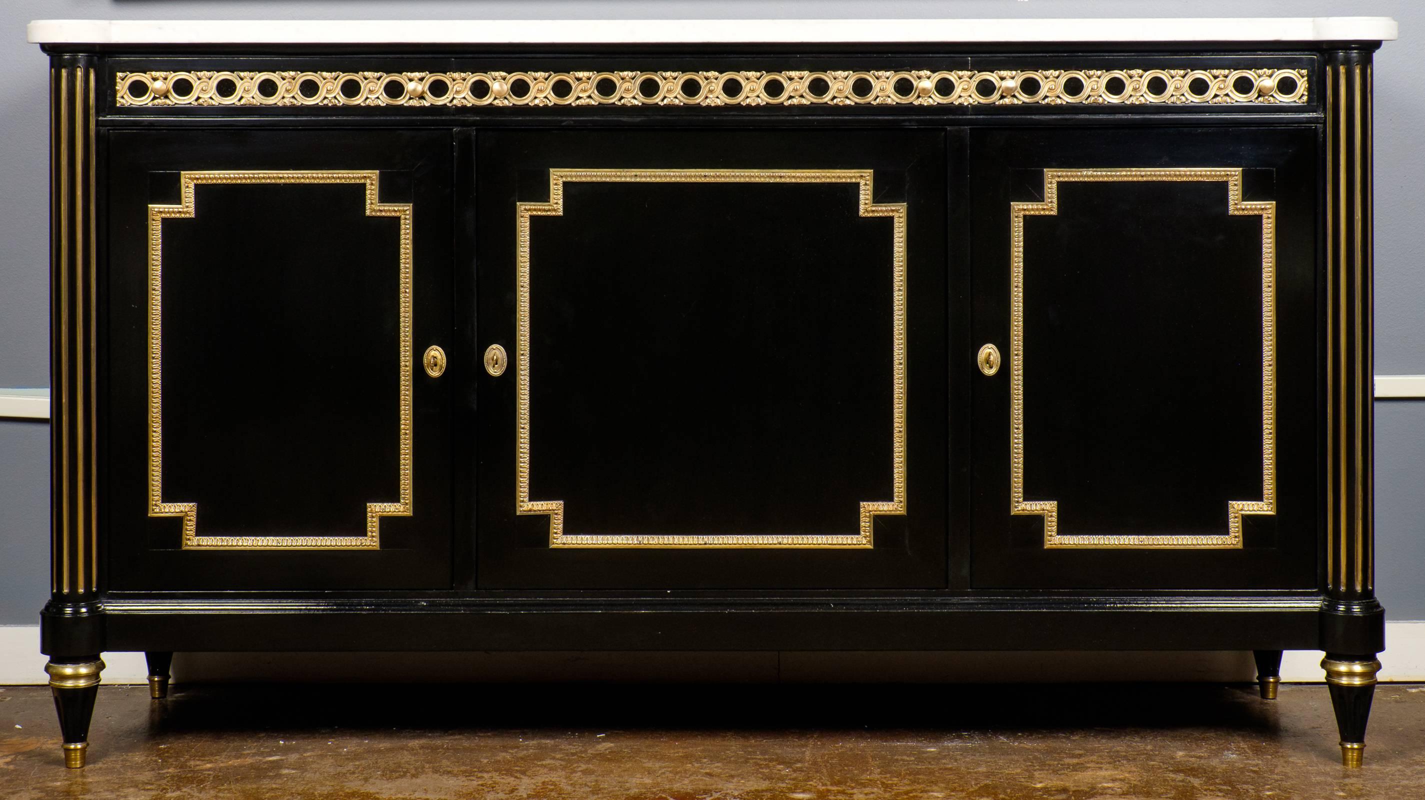 19th century Louis XVI style buffet in solid mahogany, ebonized with a lustrous French polish, original Carrara marble top. Three dovetailed drawers and three doors gleam with bronze décor. The polished mahogany interior is complete with adjustable