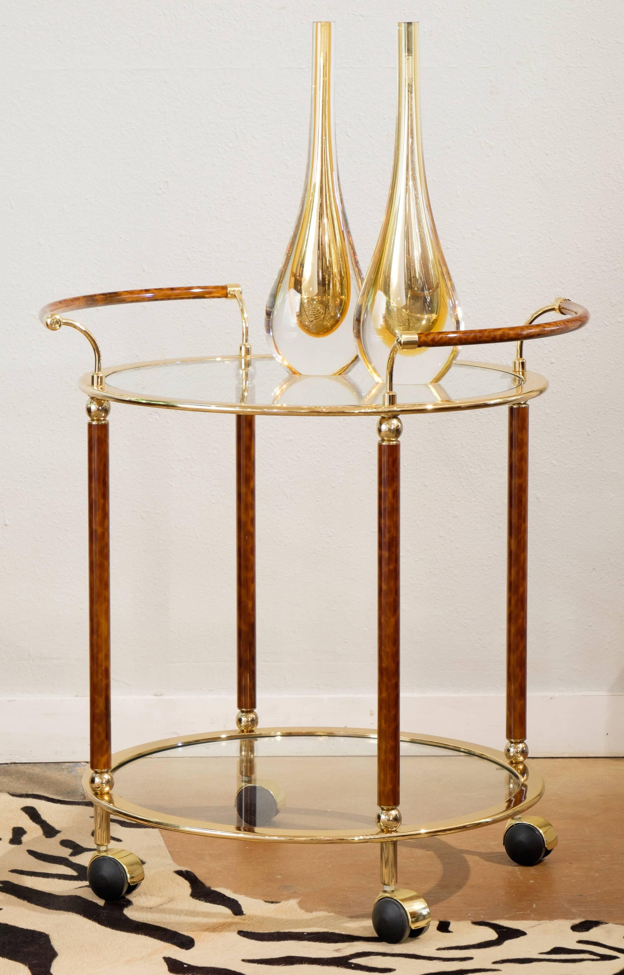 An elegant vintage French round brass glass top bar cart by Maison Lancel with faux tortoise shell on casters for ease of mobility. This rich and warm piece makes a handsome bar cart worthy of the world best Pimm's cup or ready to be a wonderful