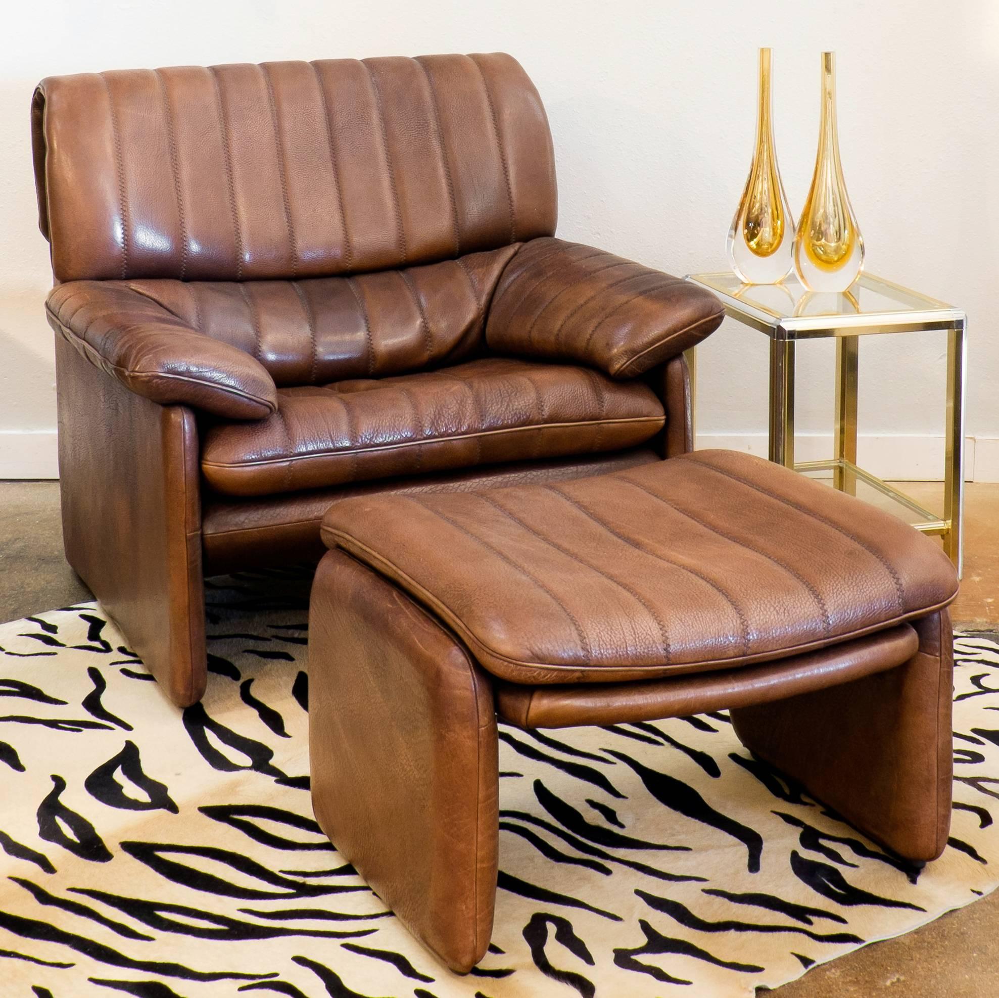 An ultra sleek vintage De Sede DS-85 soft leather armchair and ottoman in a sepia brown. This Swiss piece from the 1970s is undeniably comfortable, cushioned by a vertical patchwork of leather. Seat height measures 16.5 inches. Look at the matching