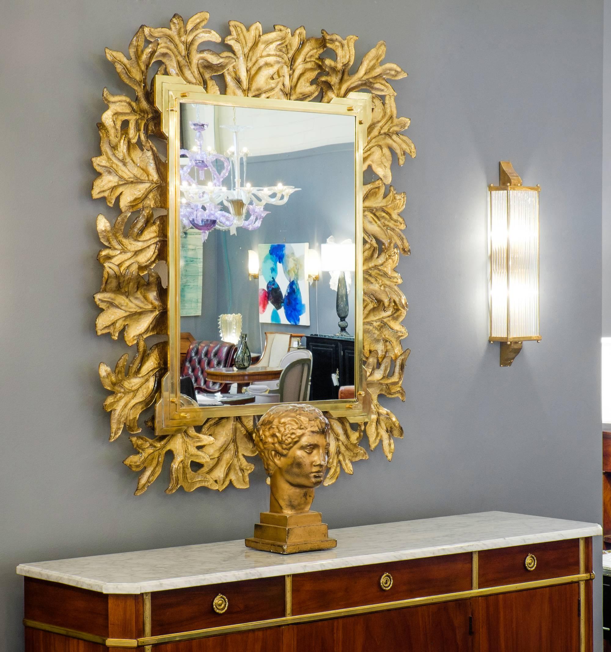 An exceptional large Murano glass gold leaf and brass mirror that takes the main stage in any room. Composed of separate gold leaf fused glass pieces that fit together in a beautiful visual chorus of foliage layers. The frame is complimented