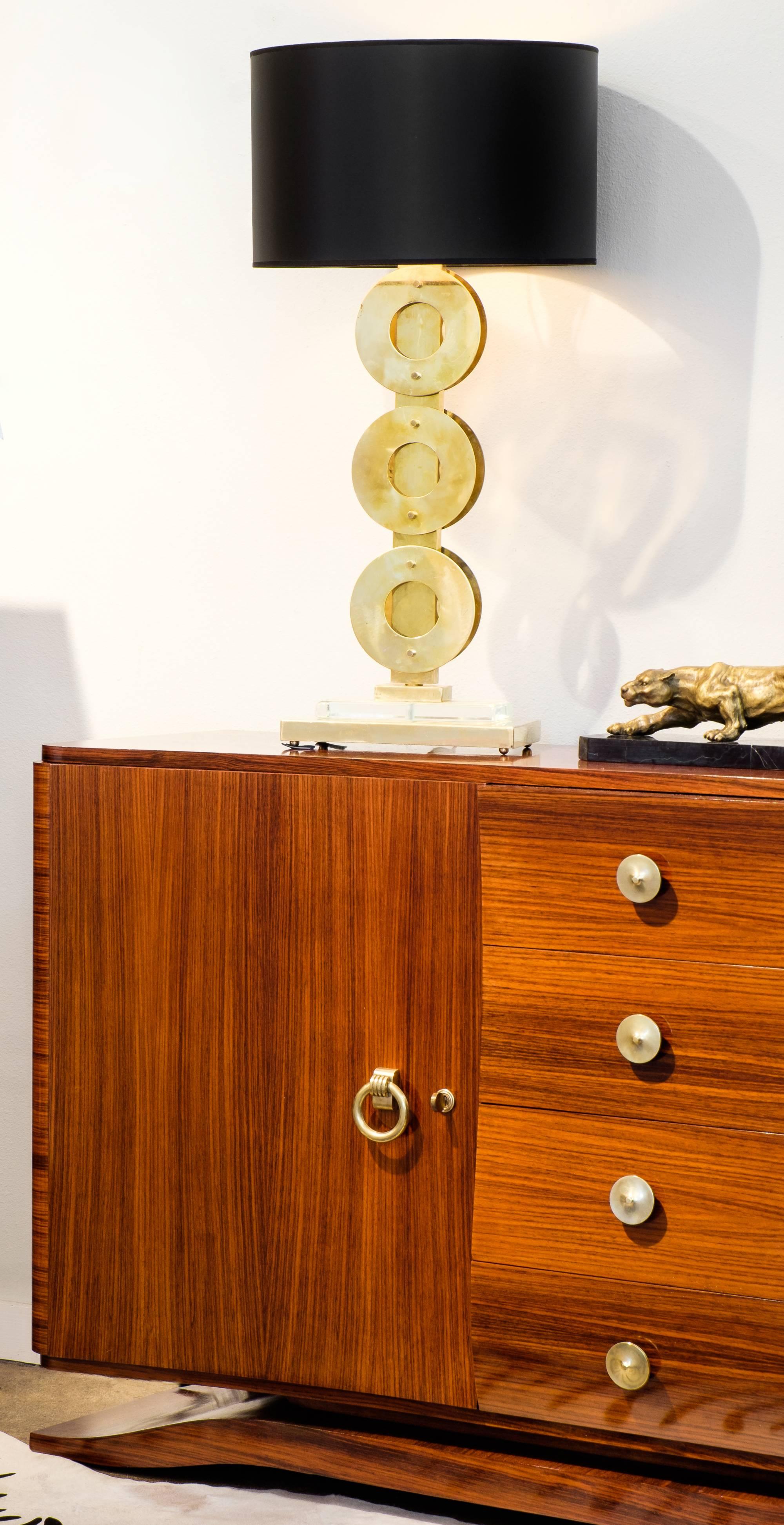 An elegant gilded brass pair of Mid-Century Modern style mounted brass circles lamps with Murano glass slabs. This gleaming duo creates a glamorous and golden glow in any interior which they are placed. We love their height which creates a dramatic