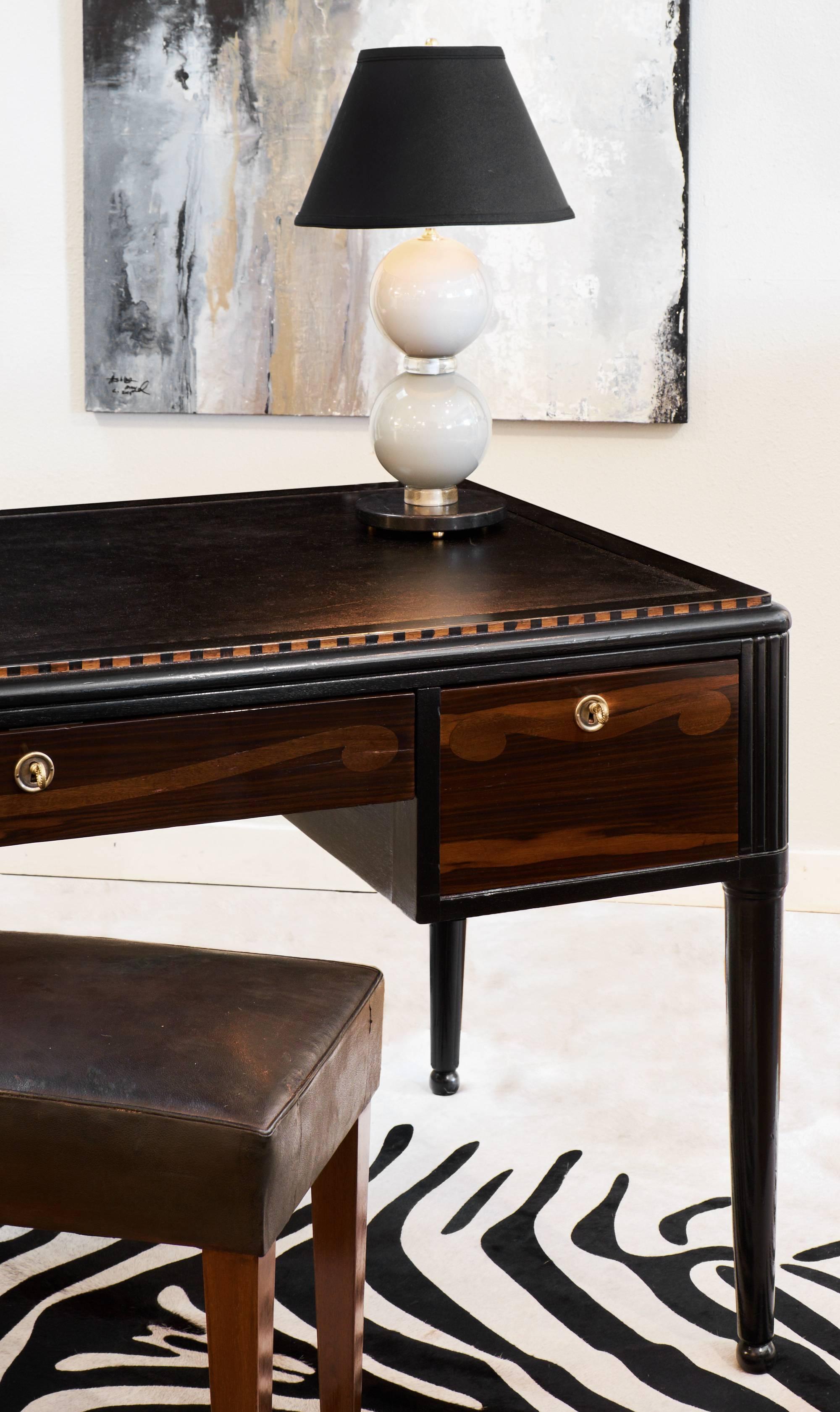 Rare French Art Deco desk of solid mahogany and tinted mahogany, in the manner of André Groult. Elegant rosewood marqueted pattern on its facade and inlaid frieze around its top. Ebonized with a lustrous French polish finish. Black moleskin top has