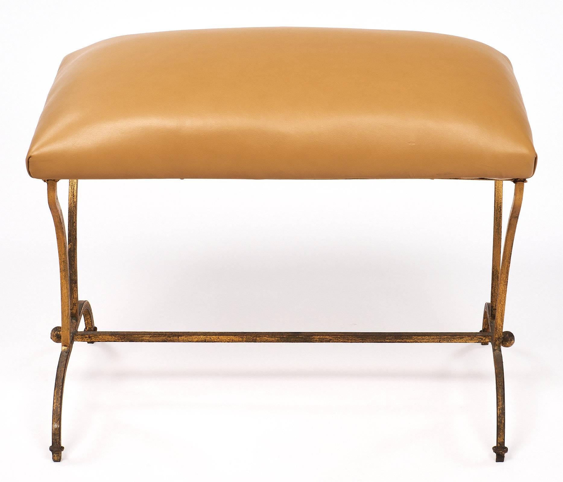 Art Deco period Spanish bench of forged iron finished with gold leaf. The cushioned seat is upholstered in a golden colored cow hide leather. A charming piece suitable for any interior.