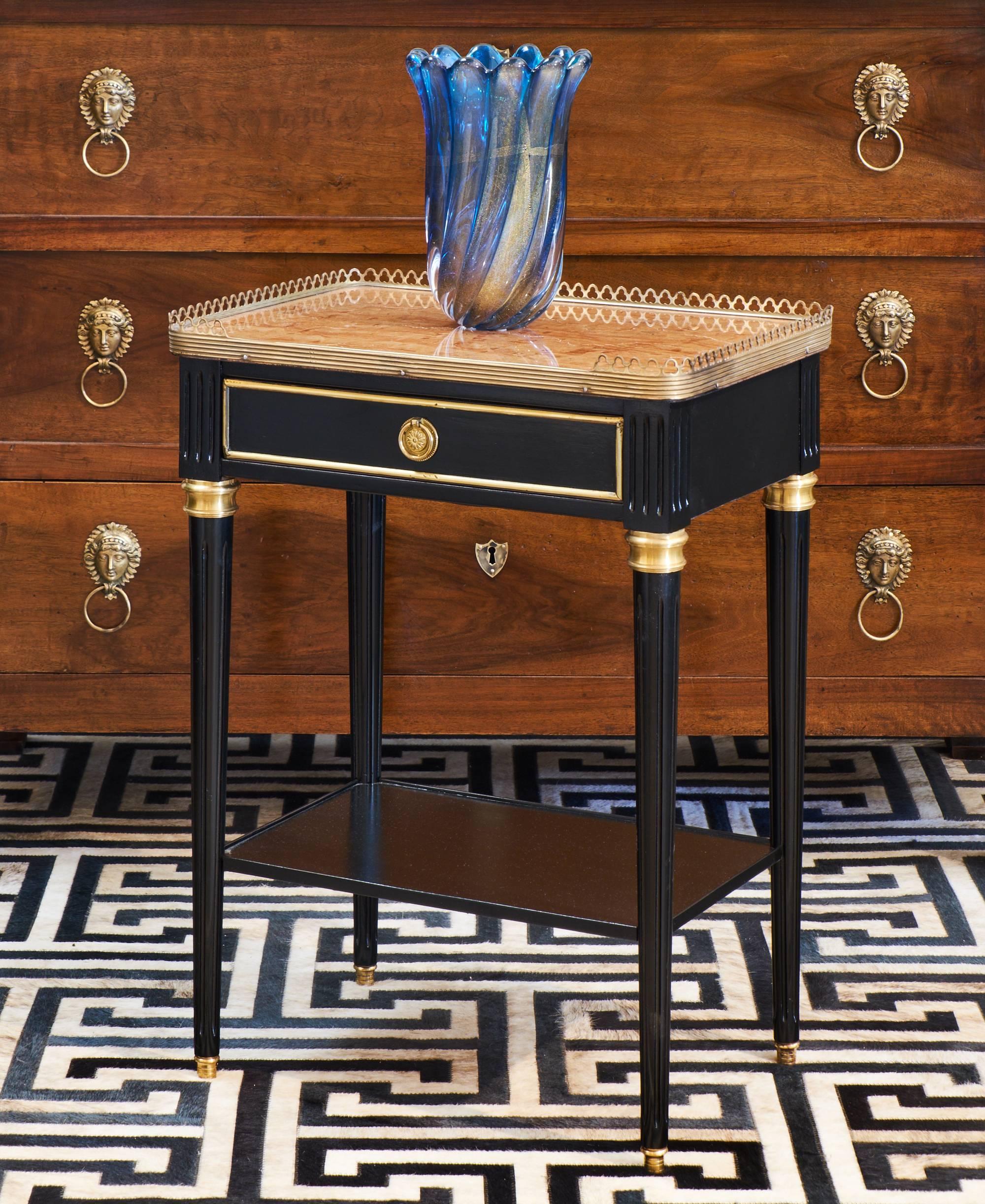 Antique French Louis XVI style side table of ebonized mahogany with a lustrous French polish finish, fluted and tapered legs, brass details, and a lovely 