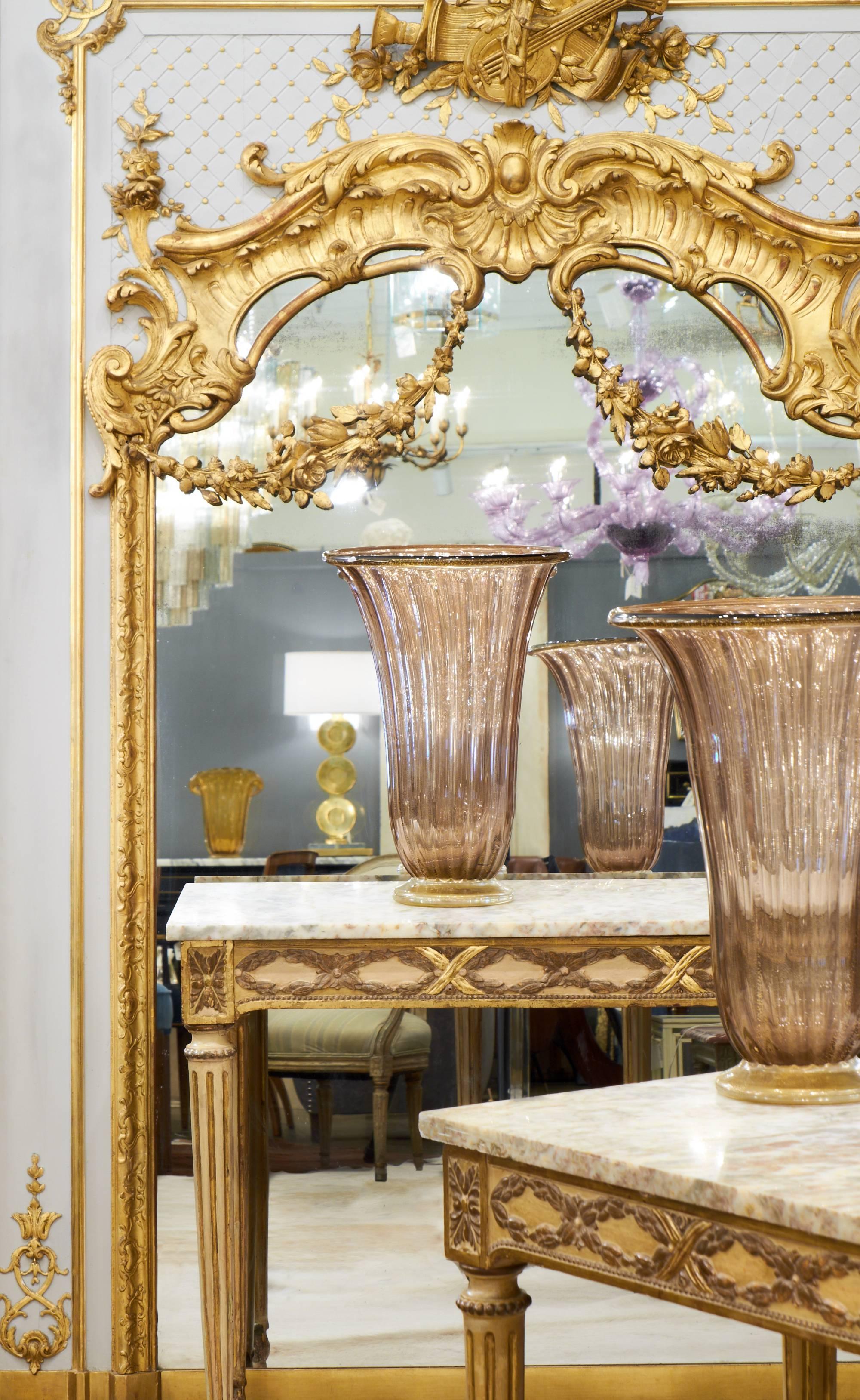 Resplendent French, Louis XVI style trumeau with magnificent, hand-carved, gold leafed décor surrounding the original mercury glass mirror. The central fronton features a lyre, music sheets and flowers. Superb carved details throughout, including