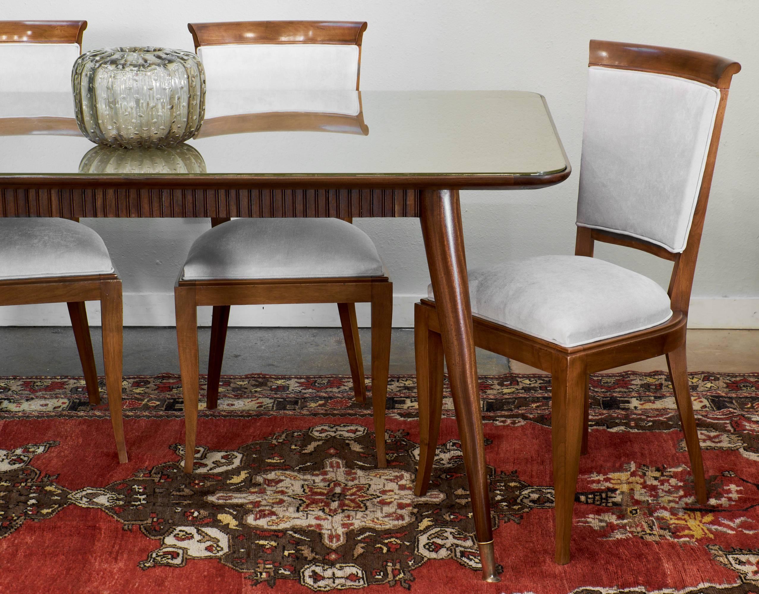 Italian Mid-Century Modern period dining room table with glass top, tapered legs with brass feet and detailed apron in the manner of Paolo Buffa.