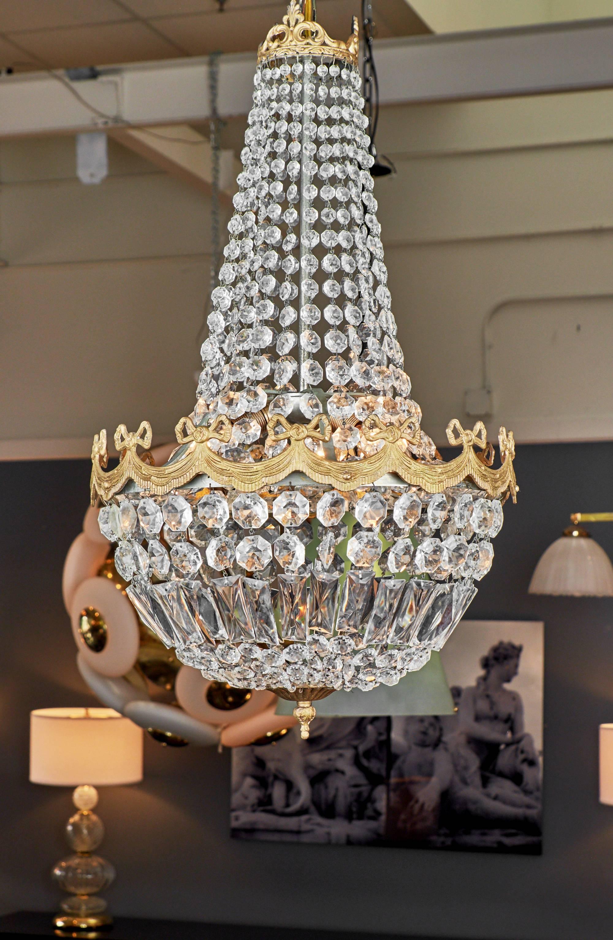 French Louis XVI style chandelier with a gilt bronze structure and brass bow details. This piece has been rewired for the US market.