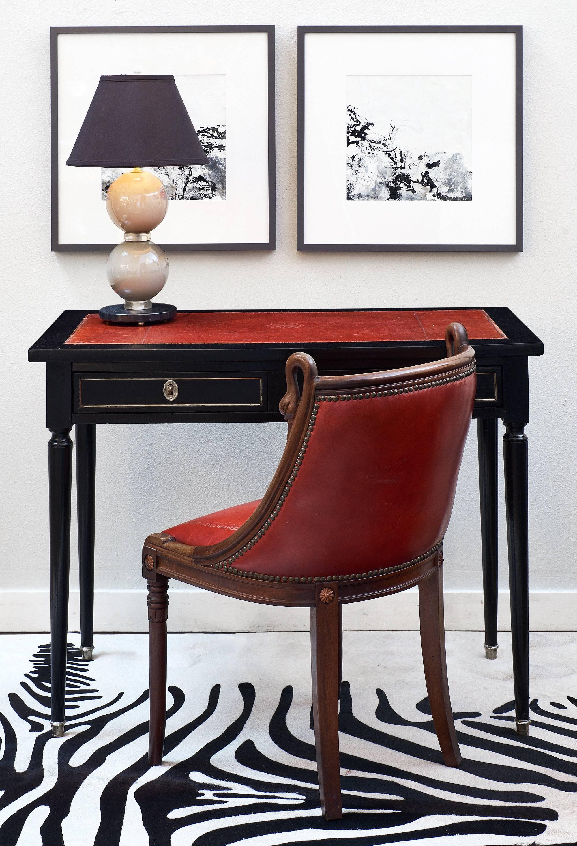 A small French antique mahogany writing desk with two drawers, each with working locks and keys. This piece features an ebonized and French polished finish for luster. The drawers and sides have gilt brass trim. The desk top and the two pull-out