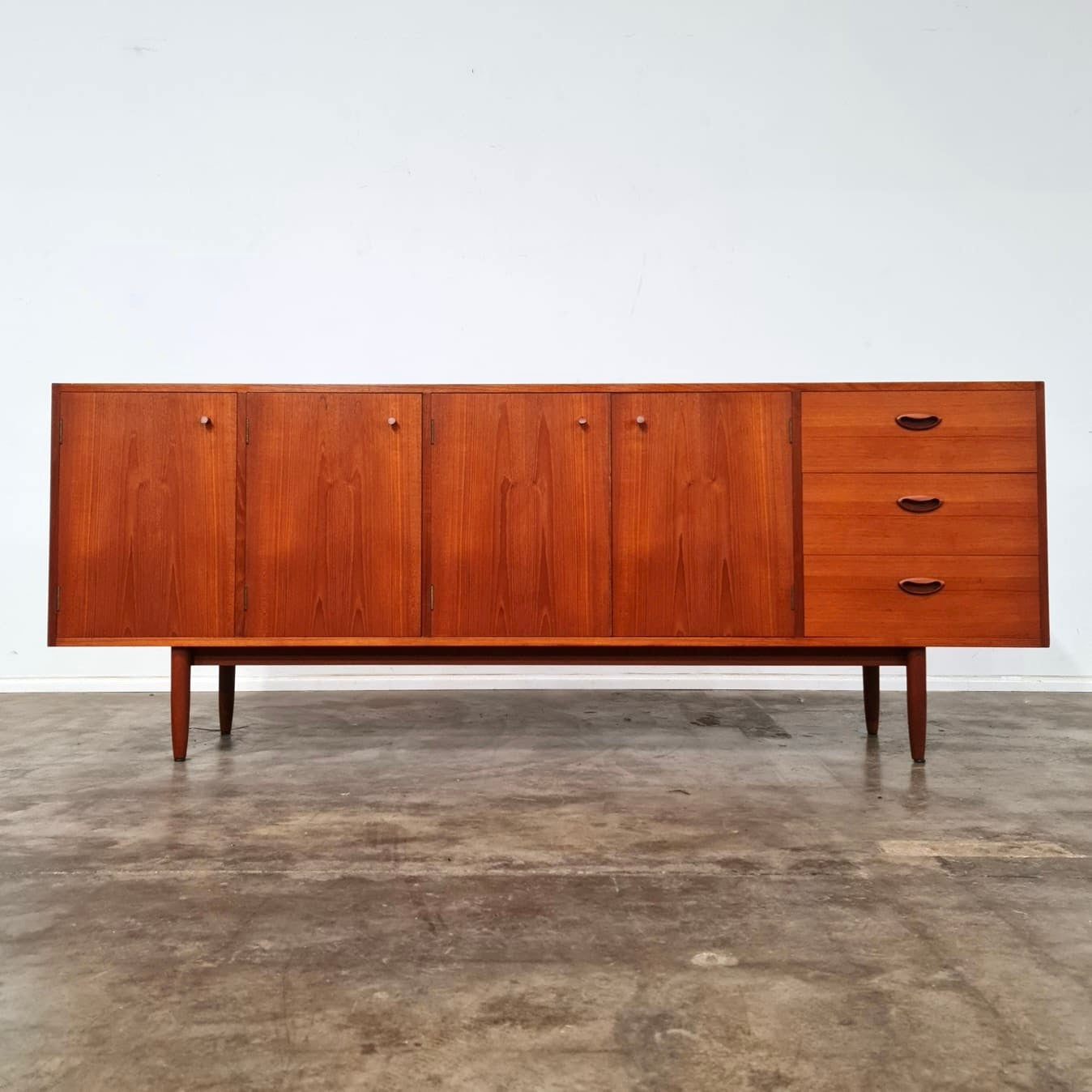 Large teak Chiswell sideboard produced in NSW Australia in May 1965. This sideboard features four doors, three drawers, bottle storage, glass storage and a cutlery drawer. Made from teak venner and solid teak legs. The top surface has been sanded