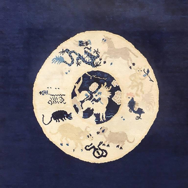 Antique collectible Chinese Zodiac rug, country of origin: Chine, circa 1900. A pleasantly simplistic indigo blue border draws the eye to the navy background the field, which further leads the viewer's attention to the circular medallion design as a