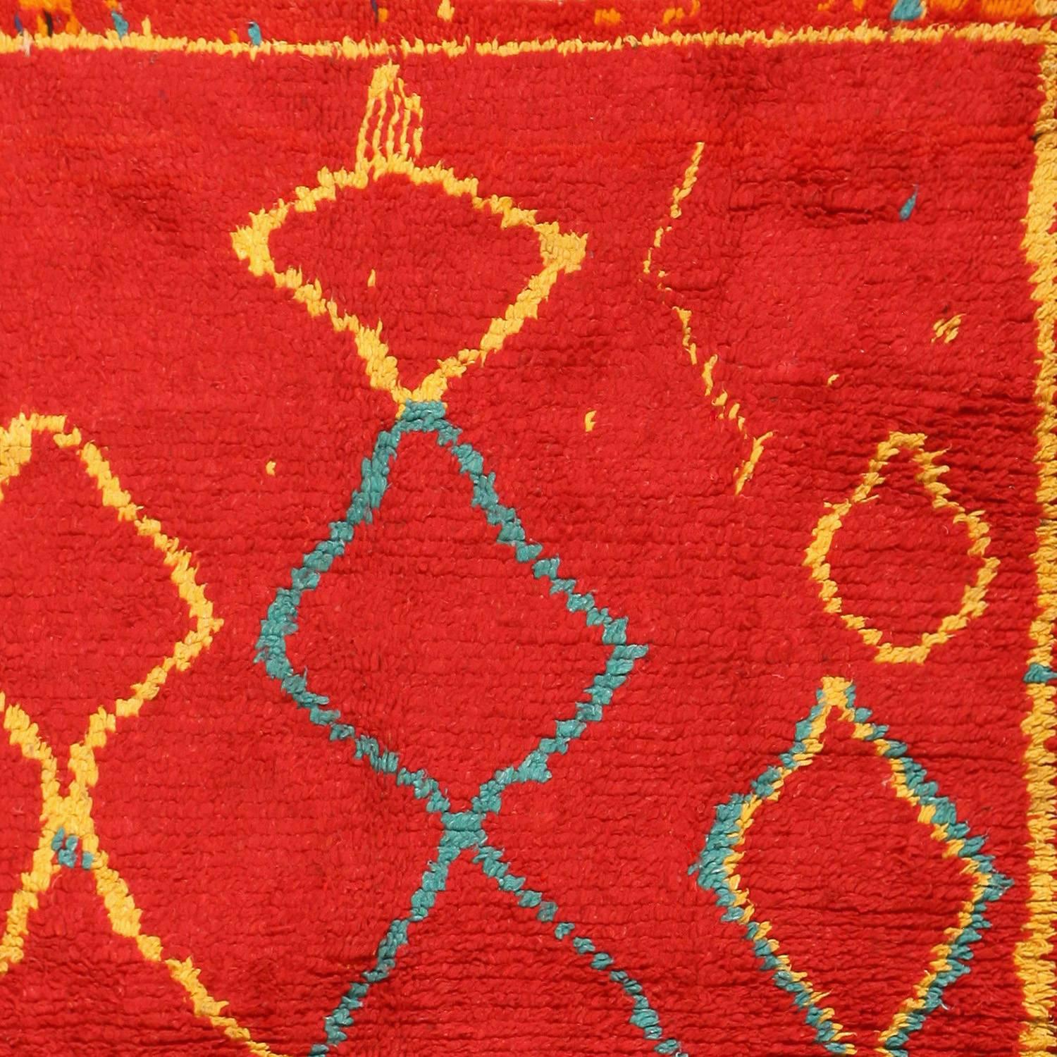 This vintage Moroccan shag rug is a vivid Berber rug, full of warmth with a red background color. Over this cheerful carmine, thickly lined figures in gentle blue and sunny yellow are picked out. Arranged singly or in pairs, the shapes are