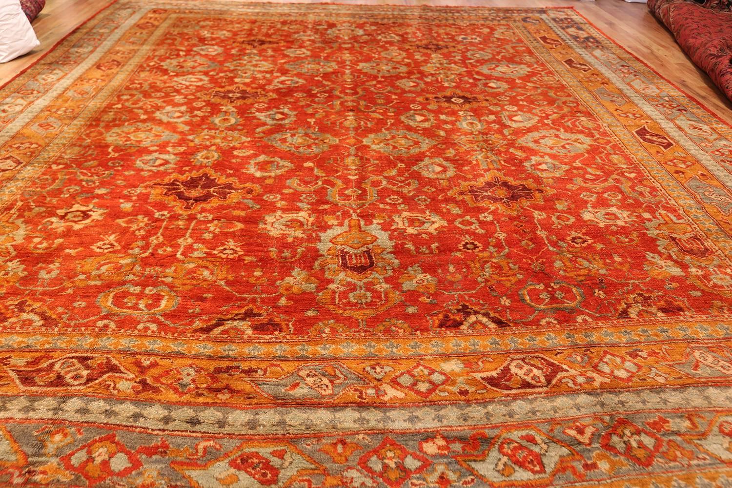 A fiery palette dominates the landscape, providing viewers with an exciting array of details that can help unify countless other elements in the room. Like many other beautiful antique Angora Oushak rug, this attractive antique rug uses a number of