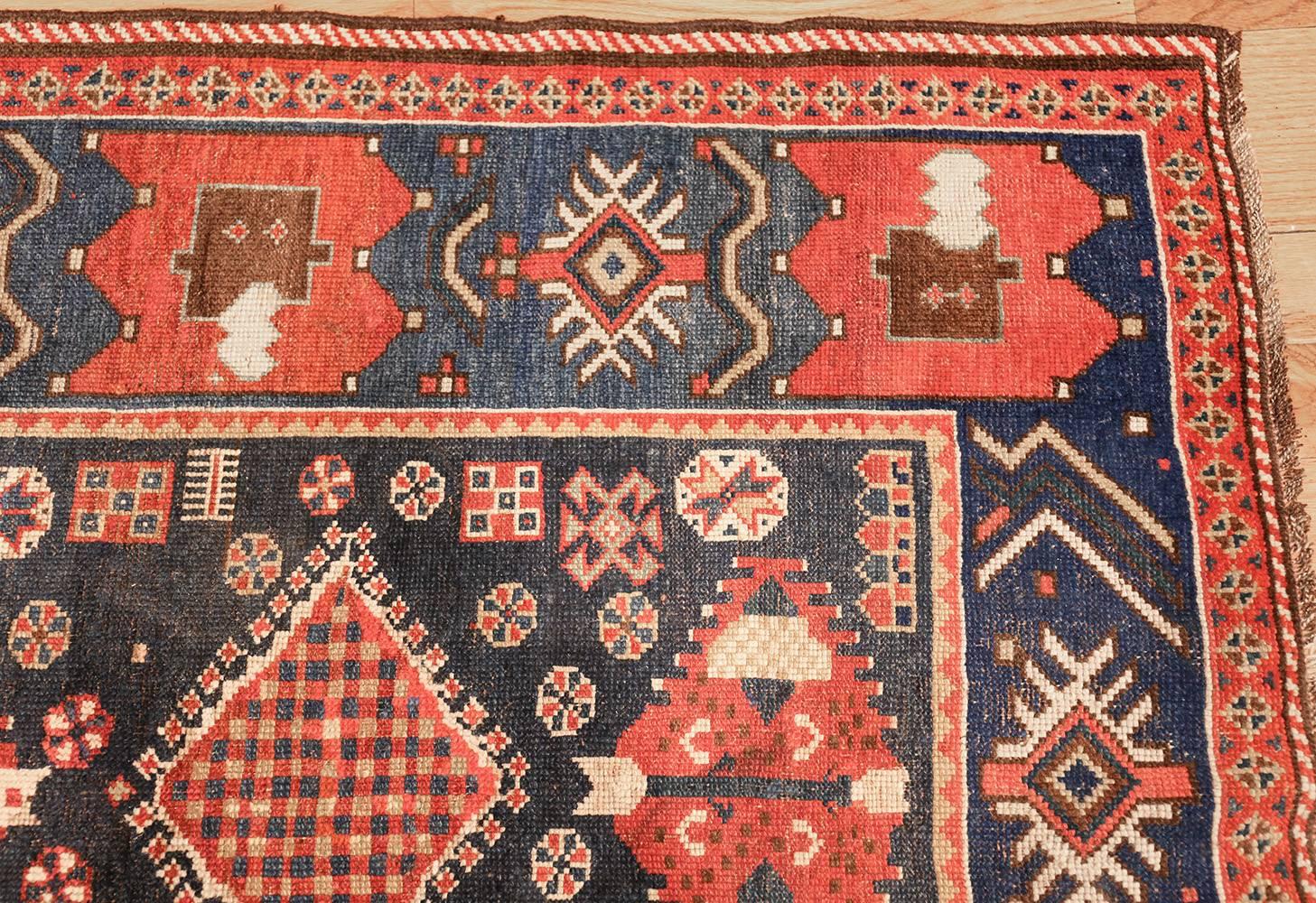 Antique Caucasian Kazak rug, country of origin: Caucasus, circa date: Early 20th century. This striking blue and red Caucasian Kazak rug features vibrant colors and carefully exact stitches that delineate the designs. The piece is mostly symmetrical