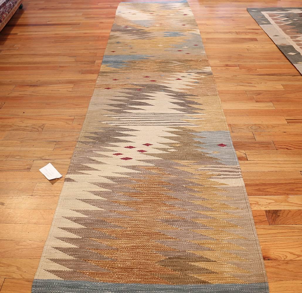 Beautiful Long and Narrow Vintage Swedish Inspired Modern Kilim Runner Rug, Country of Origin: India, Circa Date: 21 Century. Size: 3 ft x 12 ft 5 in (0.91 m x 3.78 m)

The gentle earthy tones and autumn colors of this Swedish kilim inspired modern