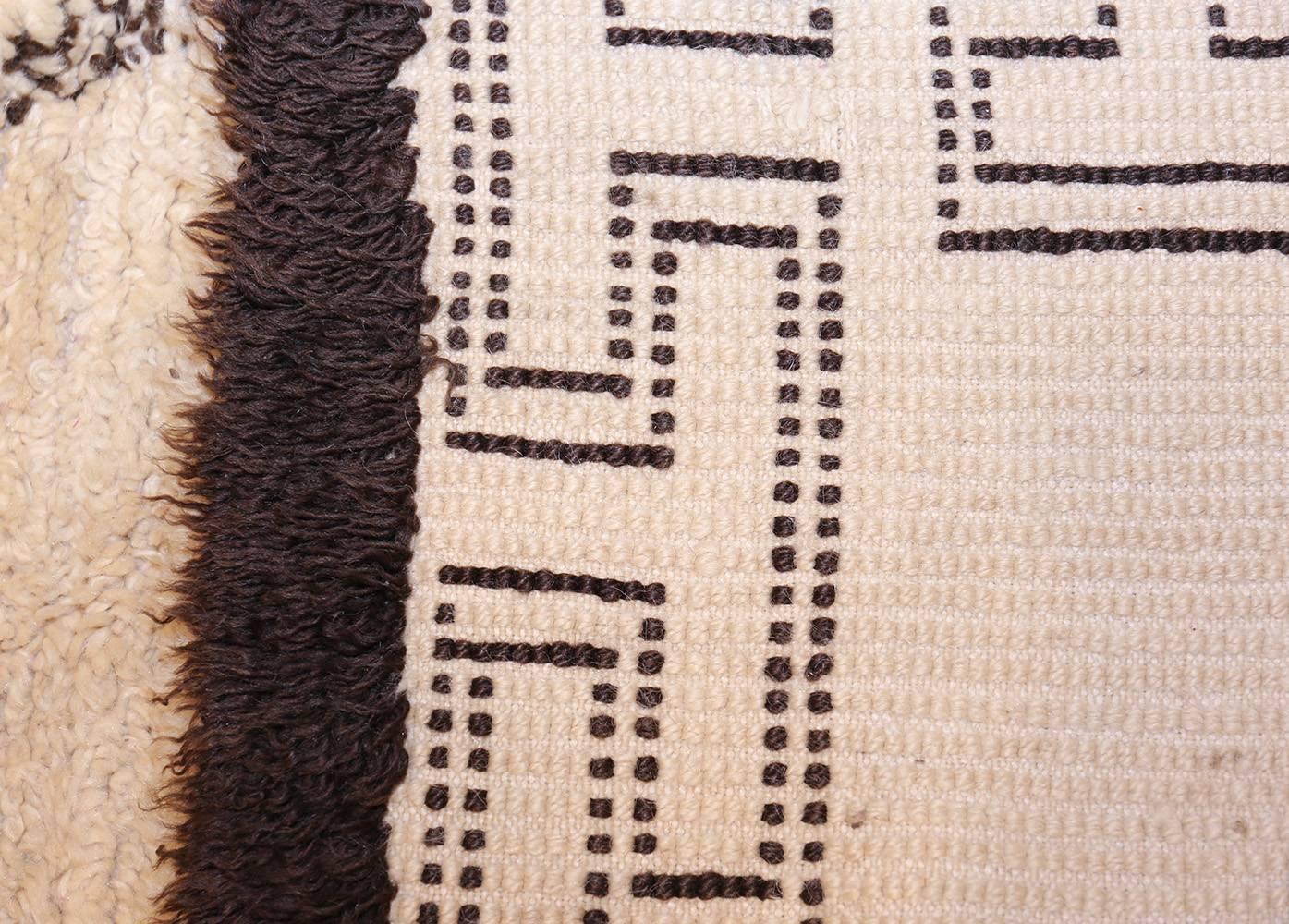 Built on esoteric traditions, this marvelous vintage Moroccan rug has a timeless style that is rich with tribal subtleties. Opulent textures and elegant achromatic hues playfully interact throughout the decorative field and ribbed end pieces, which