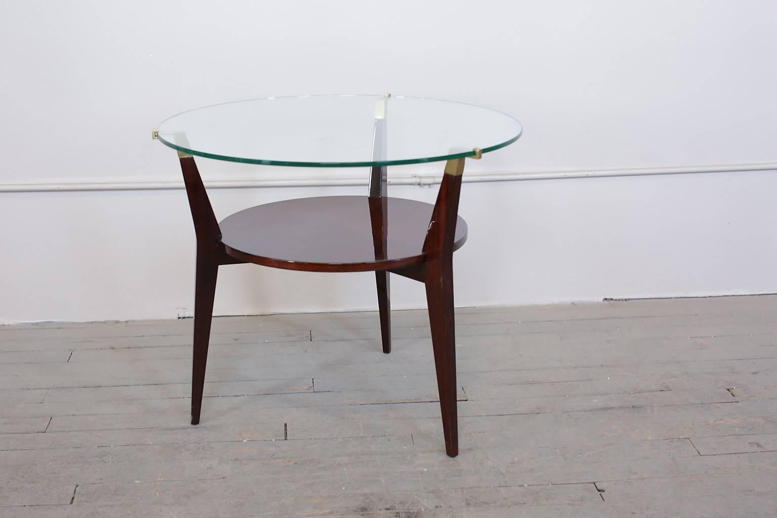 Mid-Century Modern walnut and glass gueridon or side table has bronze details. Glass top surface. Walnut shelf below.