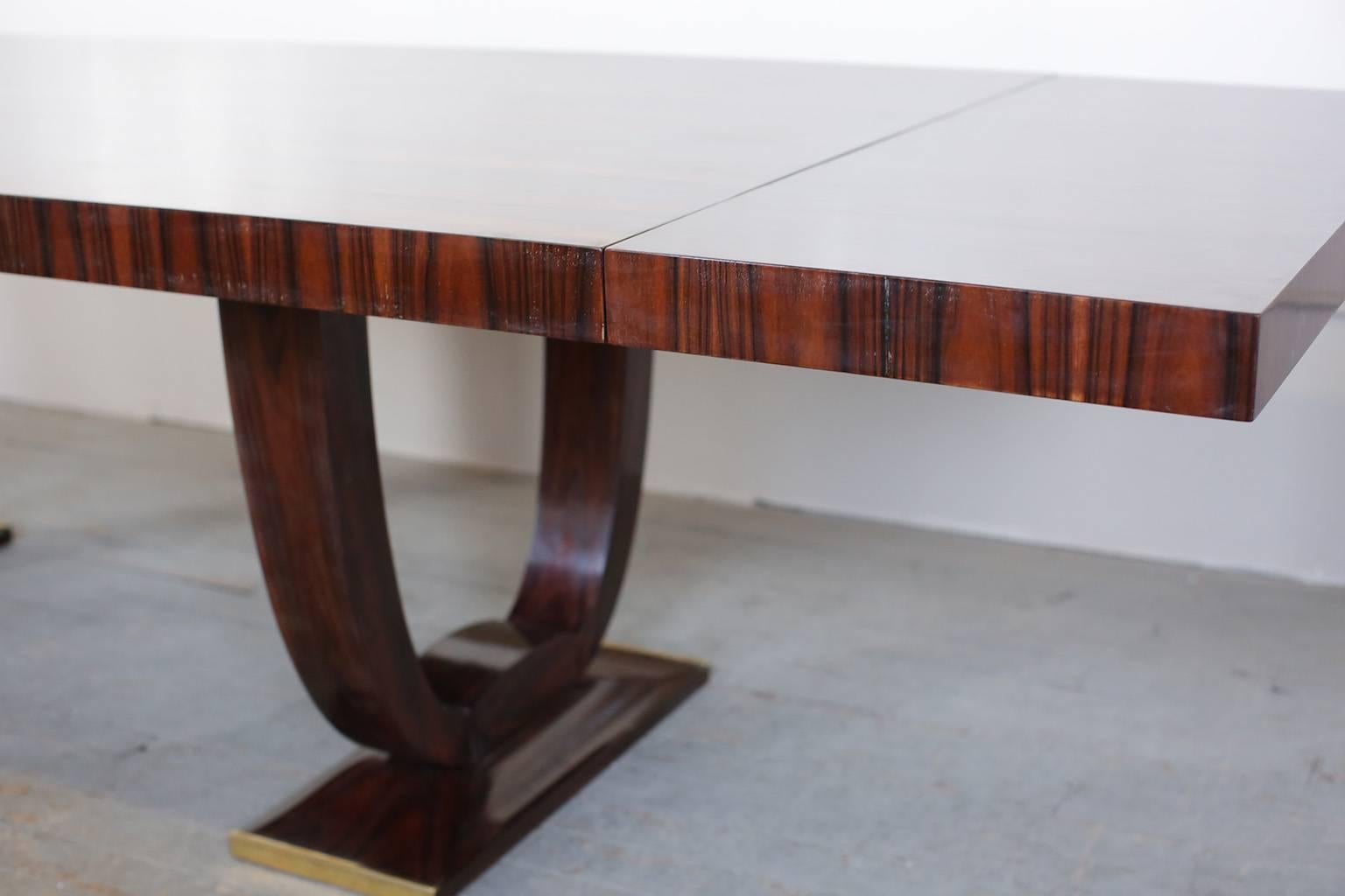 French Art Deco Rio palissandre dining table with bronze detail at the base. It comes with two matching finished extensions. (20 inches each).
