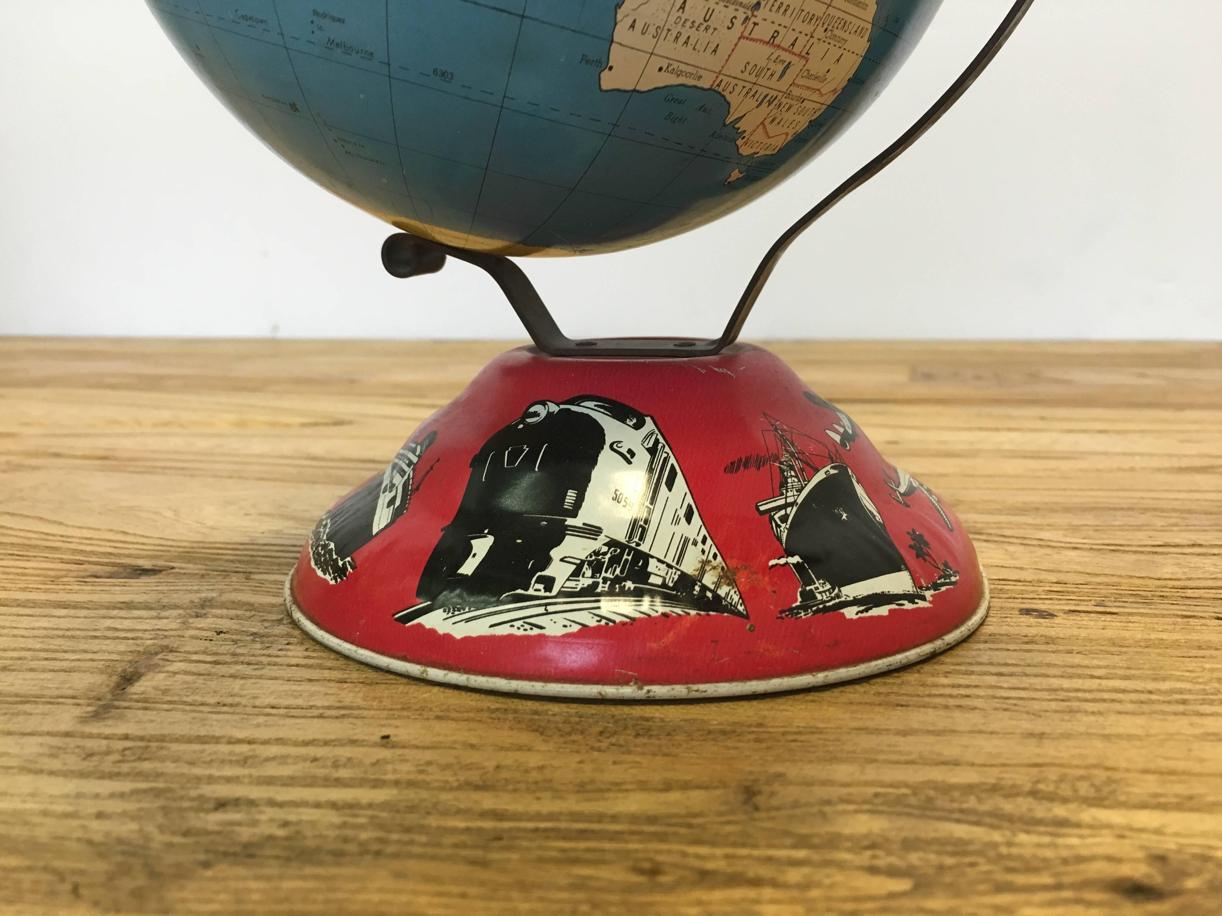 Mid-Century Ohio Arts tin globe with transportation imagery around the base. Freight train, steamer, buses, automobiles, planes, and trucks pictured.
